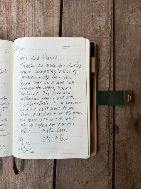 Open notebook with handwritten letter on wooden surface, with a green clip on the right side.