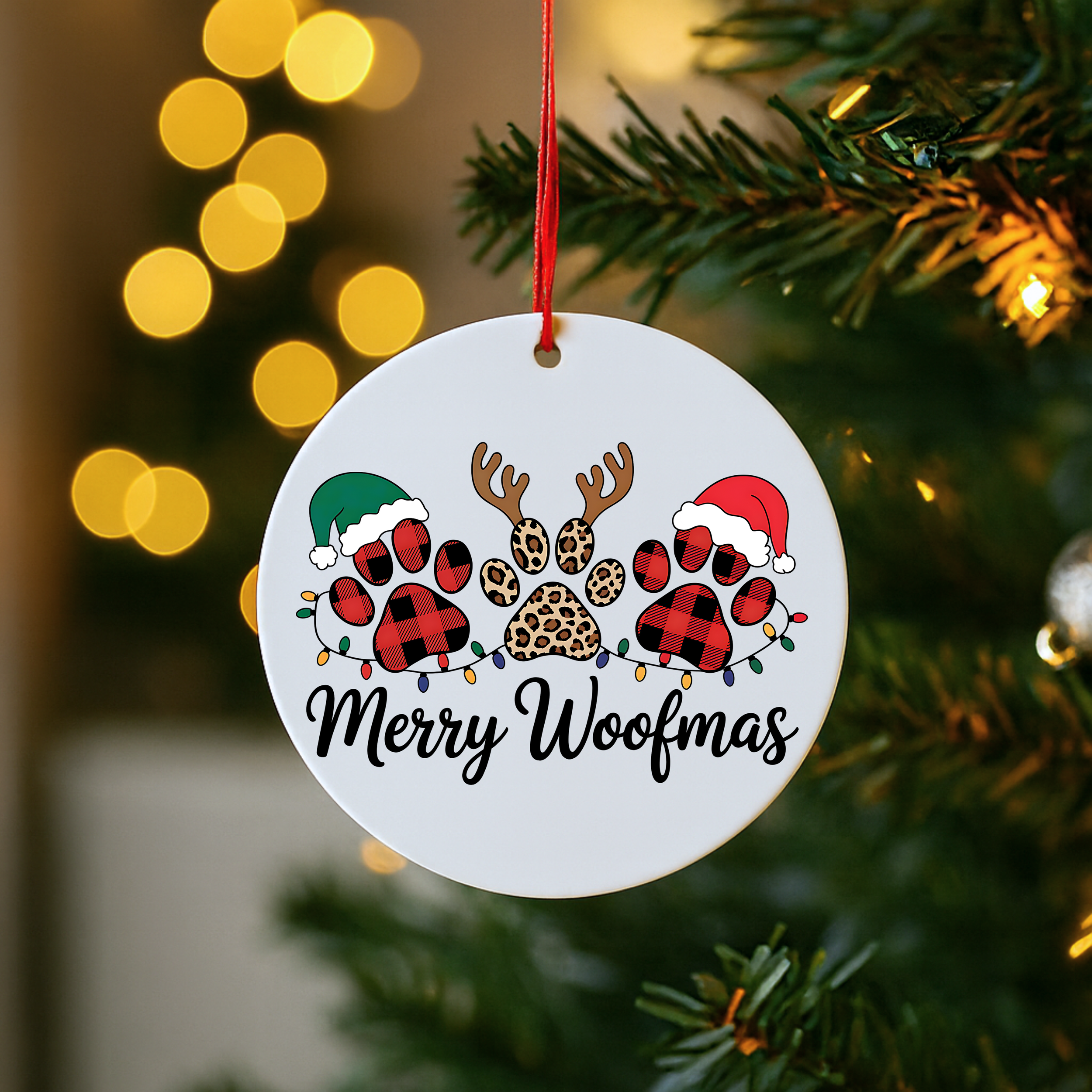 Close-up of a Merry Woofmas dog Christmas ornament featuring festive paw prints hanging on a tree.