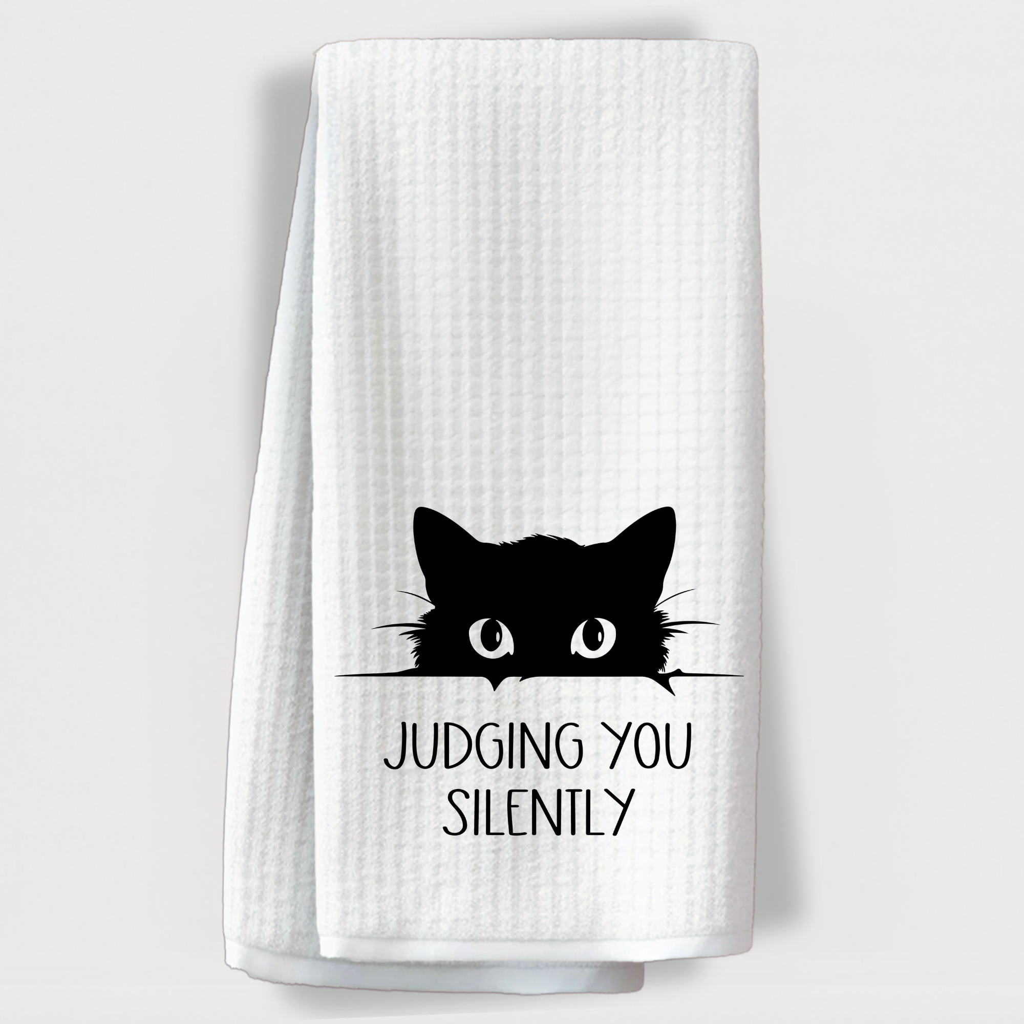 Hilarious towel with a black cat peeking over a ledge and the phrase 'Judging You Silently'