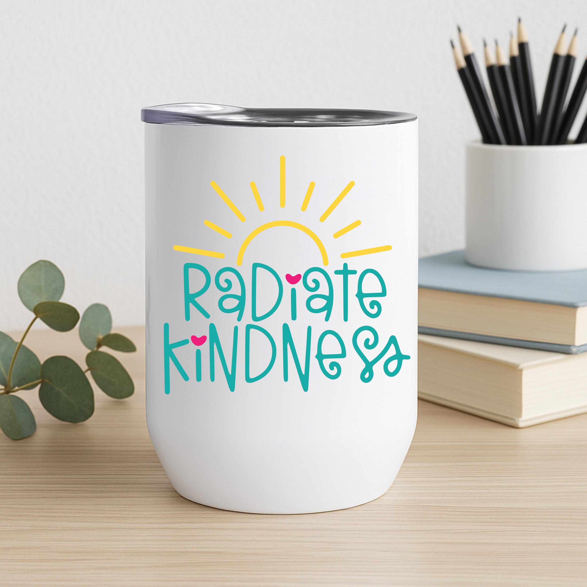 Radiate Kindness stainless steel tumbler on desk with books, pencils, and greenery