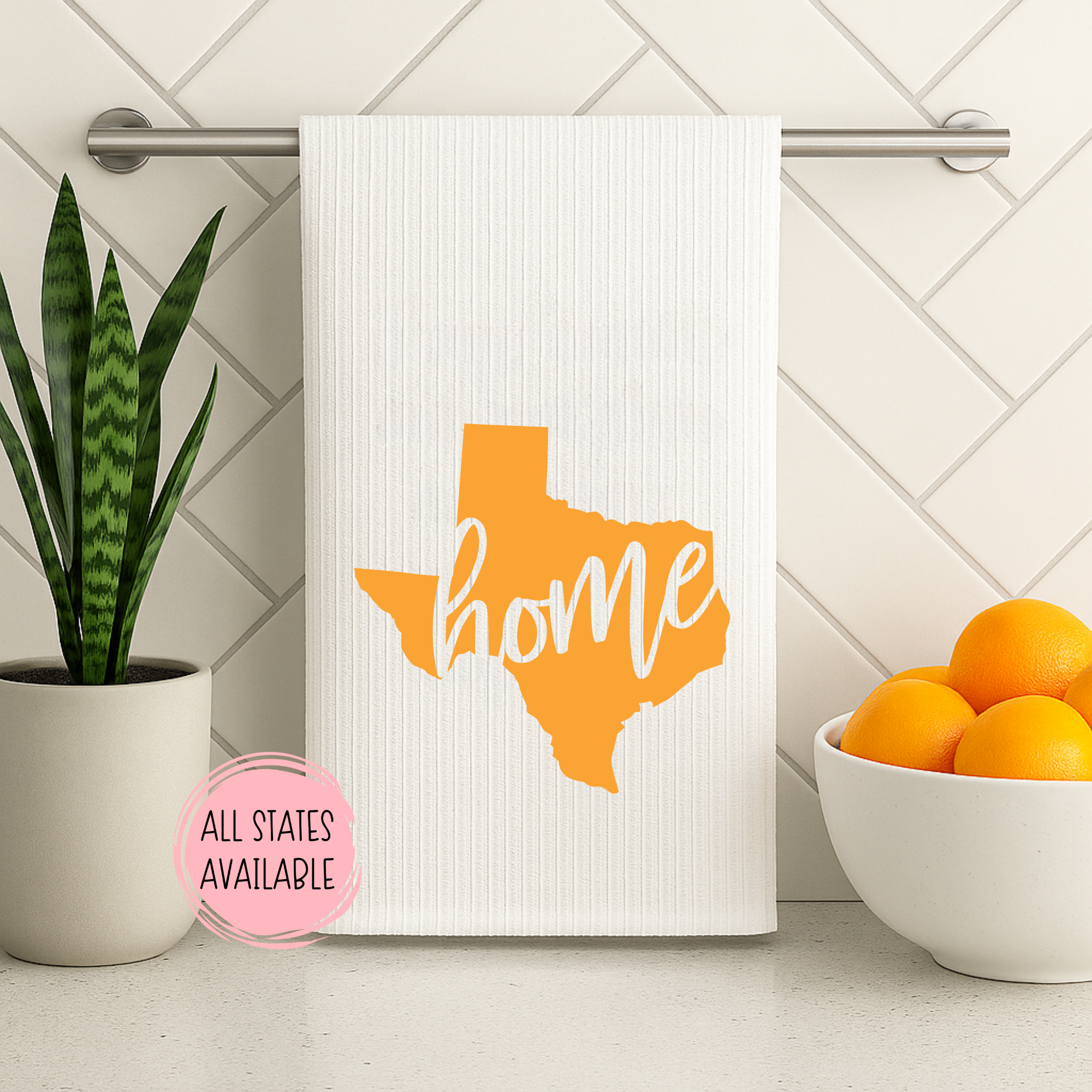 Modern kitchen towel featuring orange Texas home state design with “home” text and plant decor.