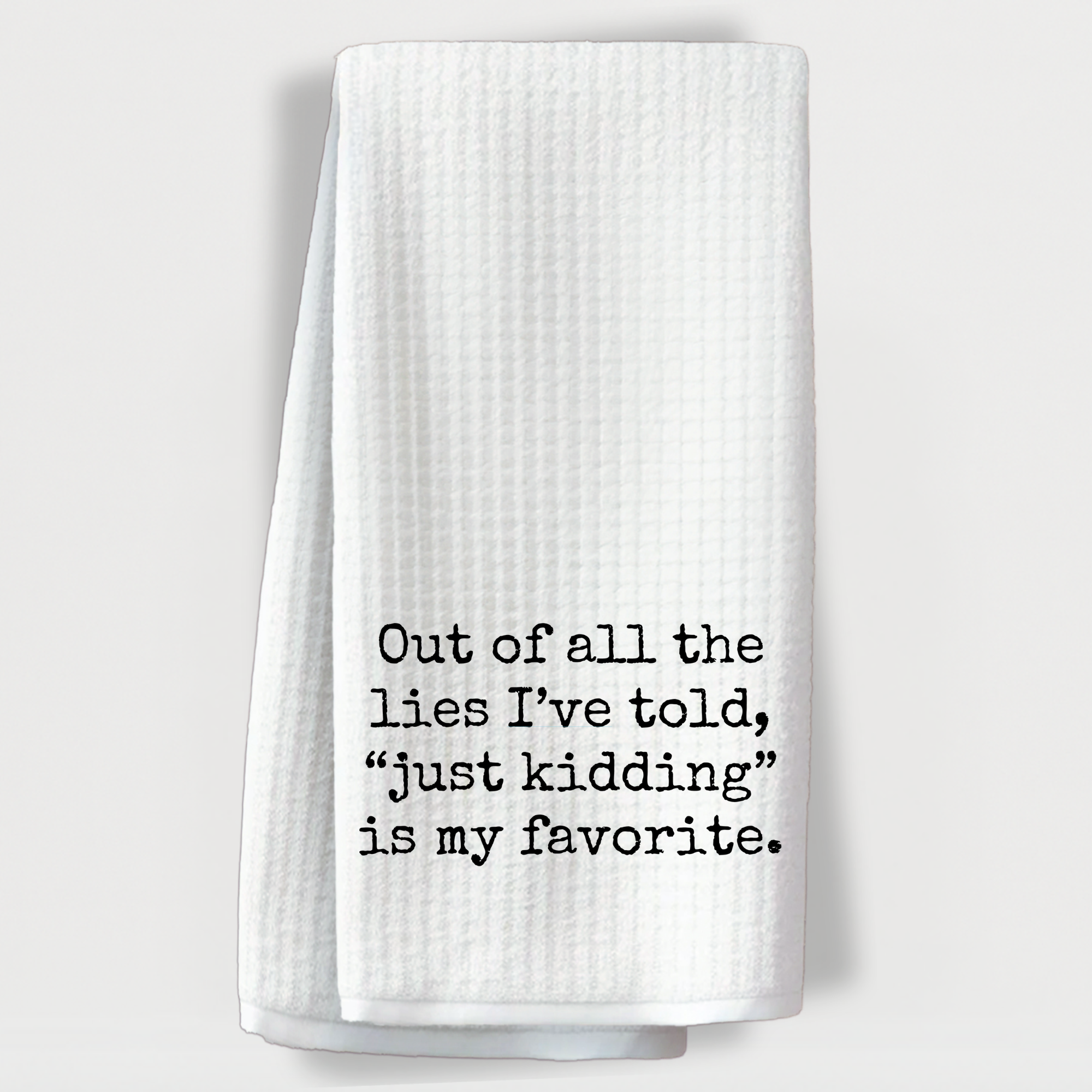 Witty dish towel with the saying 'Out of all the lies I’ve told, “just kidding” is my favorite'.