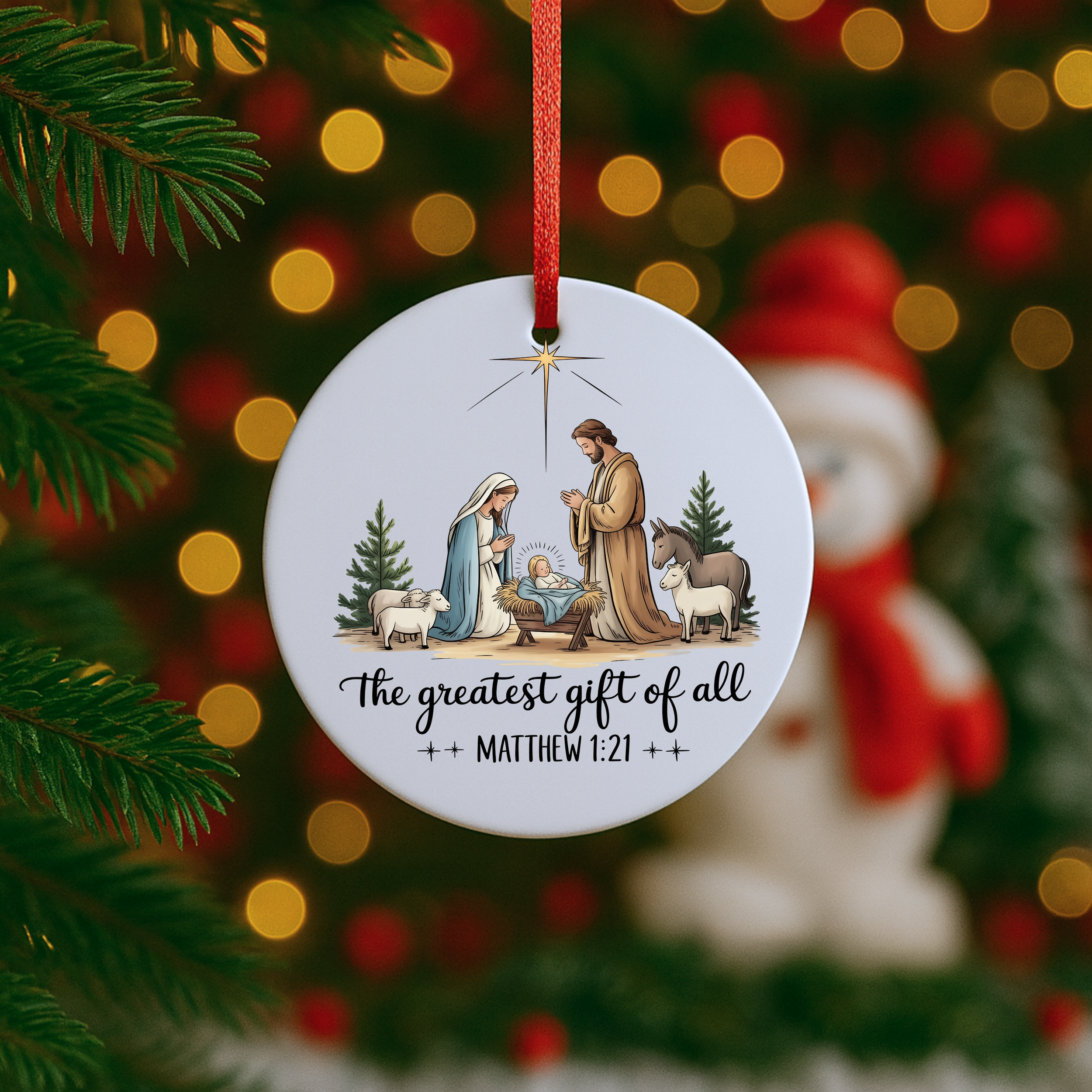 Christian nativity ornament hanging on a Christmas tree with Santa decor blurred in the background.