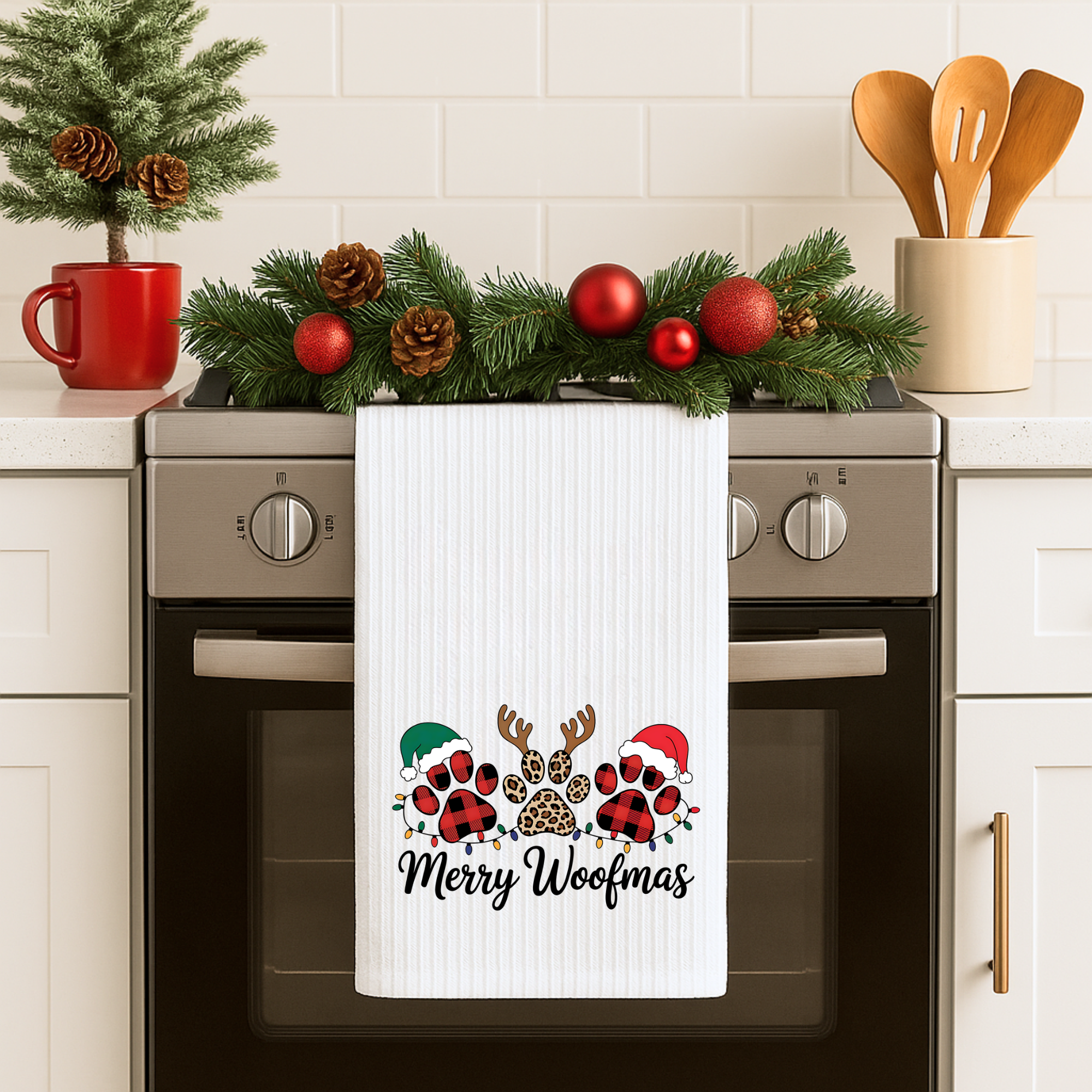 Merry Woofmas dog Christmas kitchen towel hanging on an oven handle with festive garland.