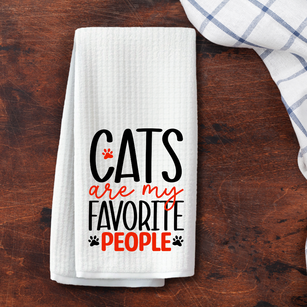 Elegant and modern waffle weave towel with "Cats are my favorite people" text, folded on a dark wooden surface for a chic kitchen look.