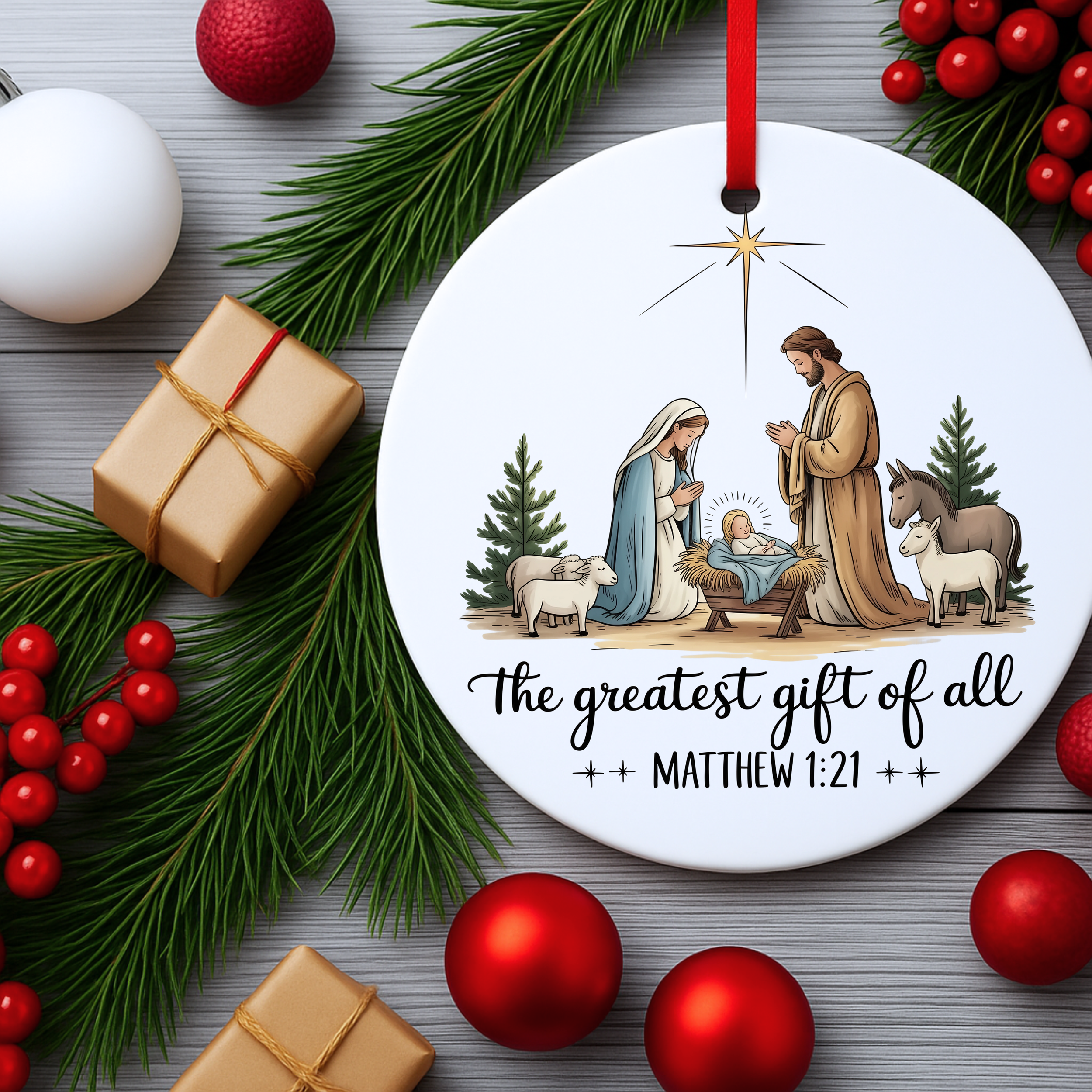 Christian nativity ornament flat lay surrounded by pine branches, red ornaments, and wrapped gifts.