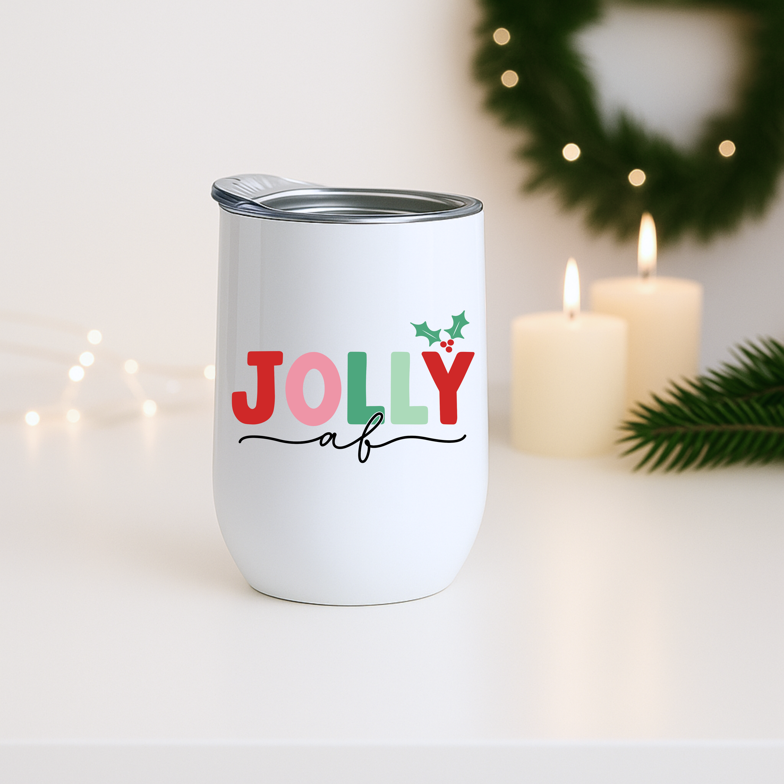 Jolly AF holiday tumbler displayed near candles and greenery with soft holiday lighting.