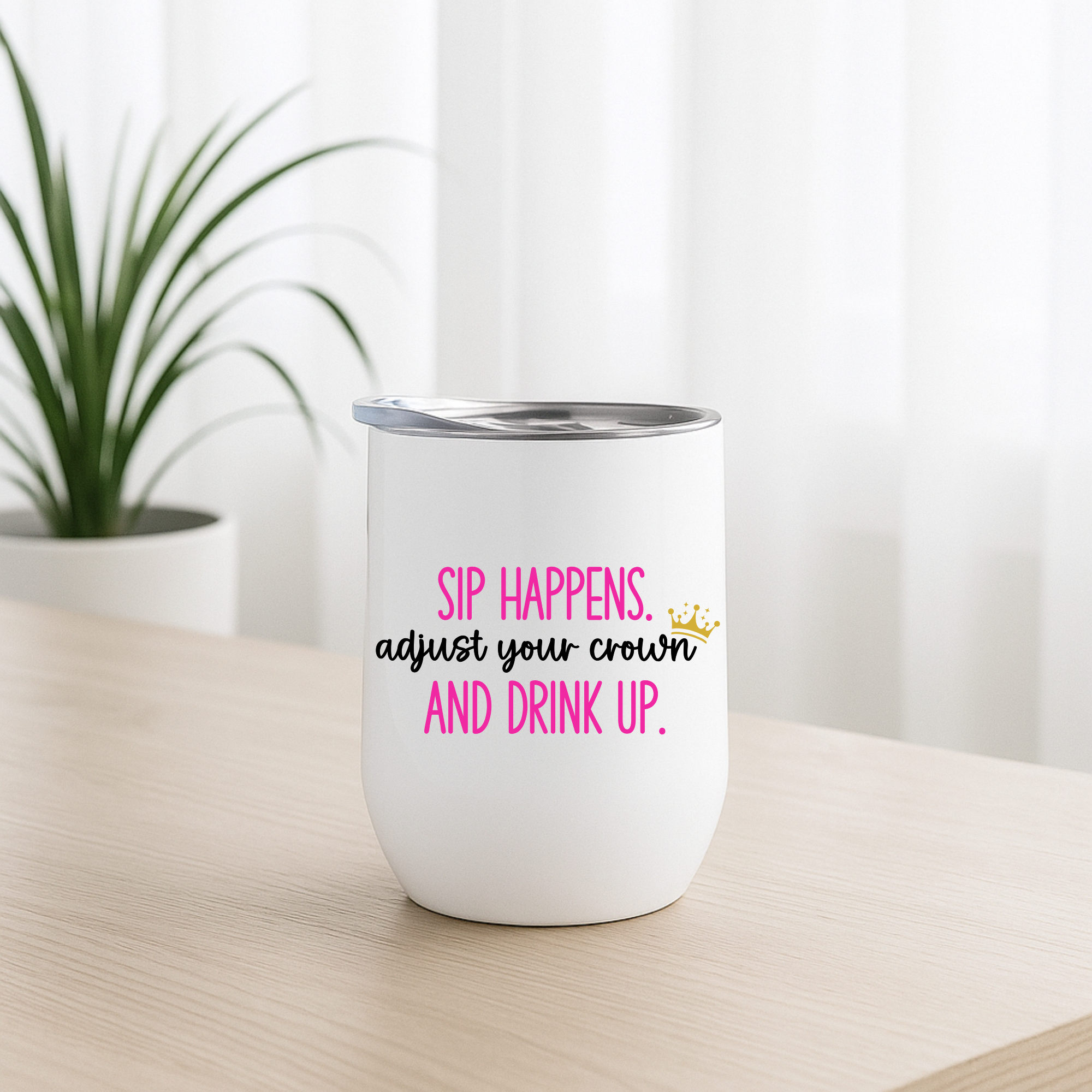 Sip Happens wine tumbler with magenta text, minimalist indoor desk.