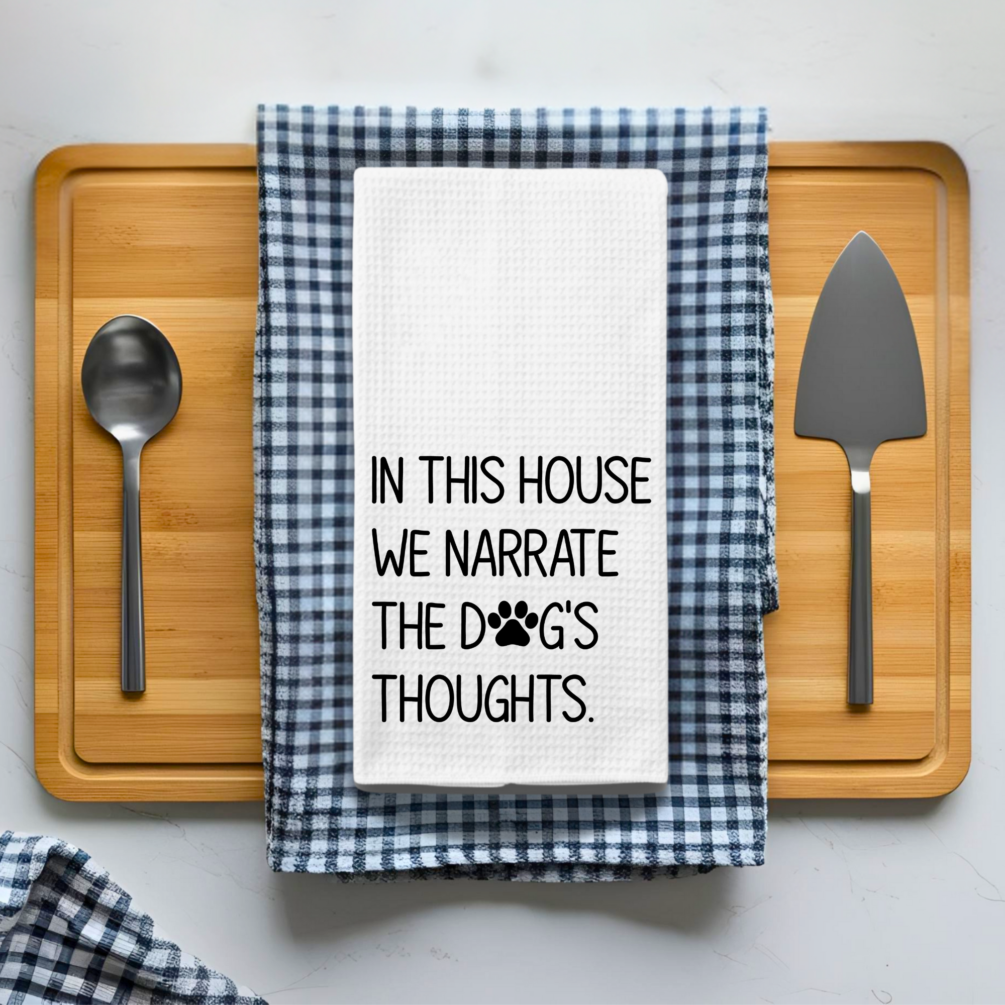 Funny quote dish towel styled on a checkered kitchen towel with serving utensils for dog lovers.