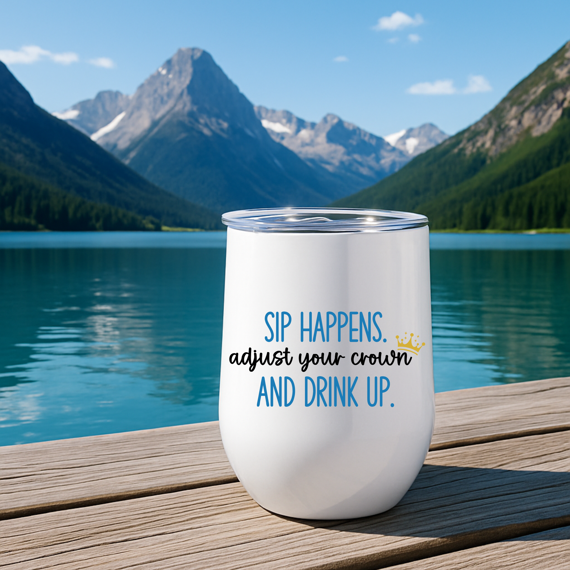 Sip Happens wine tumbler with blue text, sitting on dock by mountains.