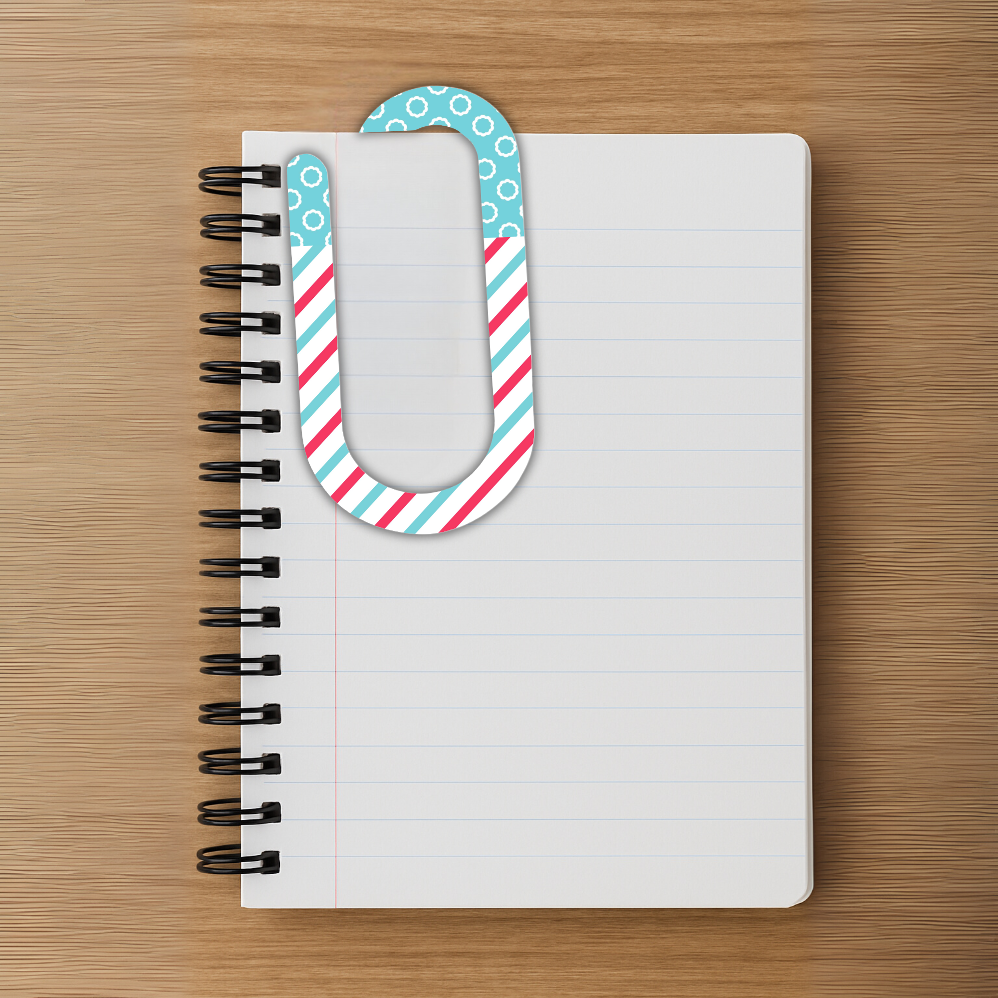 Striped acrylic clip holding pages in a spiral notebook on wood desk.