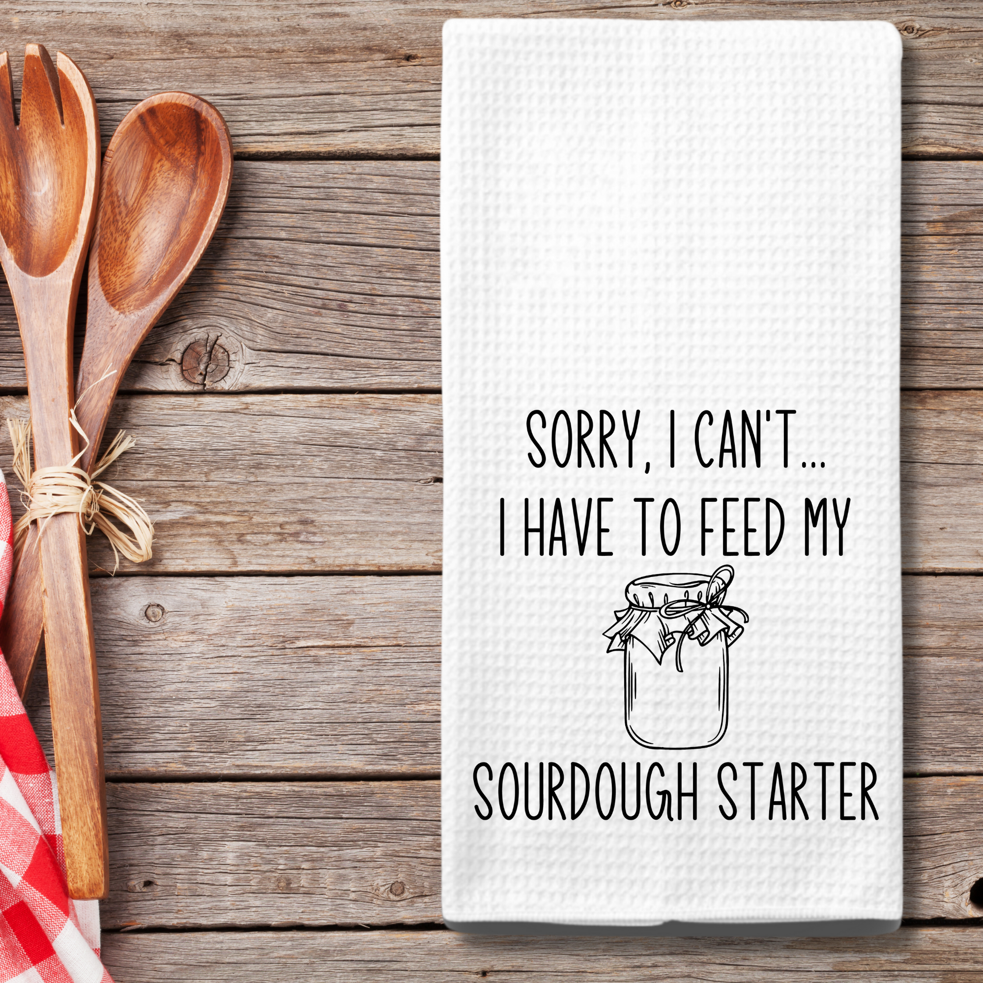 Funny tea towel flat lay with wooden utensils and red gingham – gift for sourdough lovers.