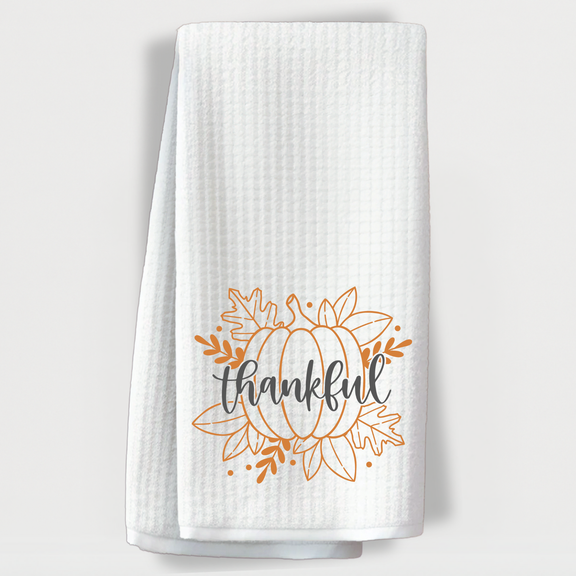 Folded fall kitchen towel with pumpkin and thankful design, farmhouse holiday decor.