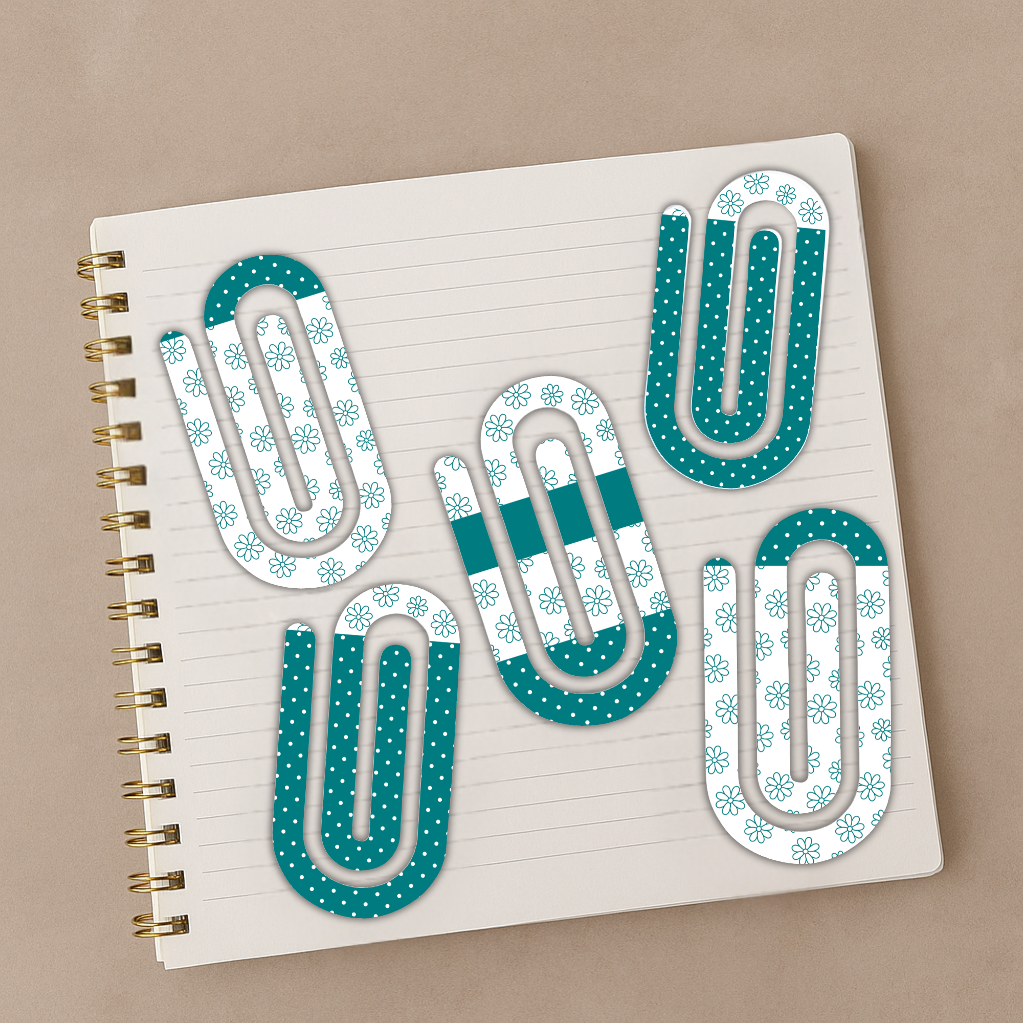 Decorative acrylic paperclips displayed on a spiral-bound notebook with a neutral background.