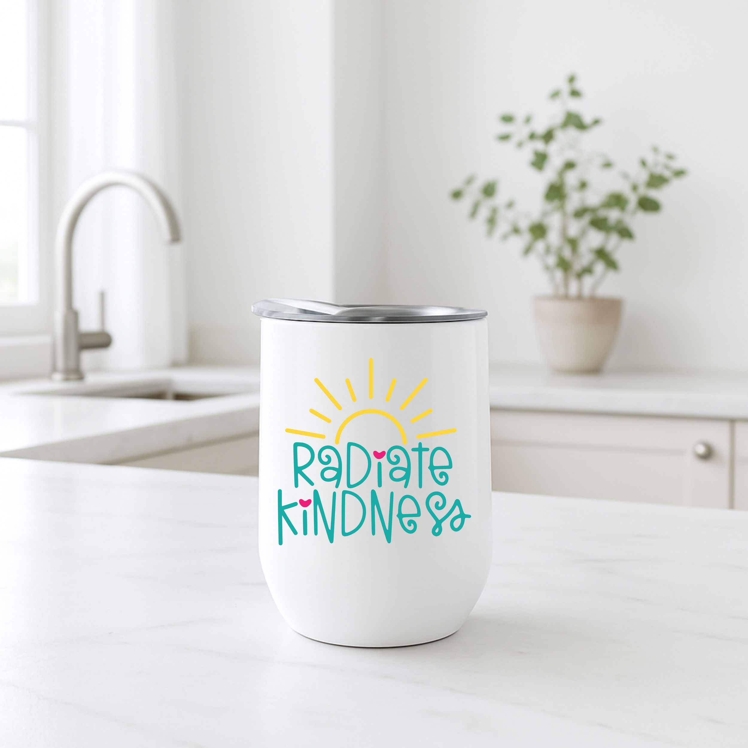 Radiate Kindness coffee tumbler on a white marble kitchen island with sink and plant