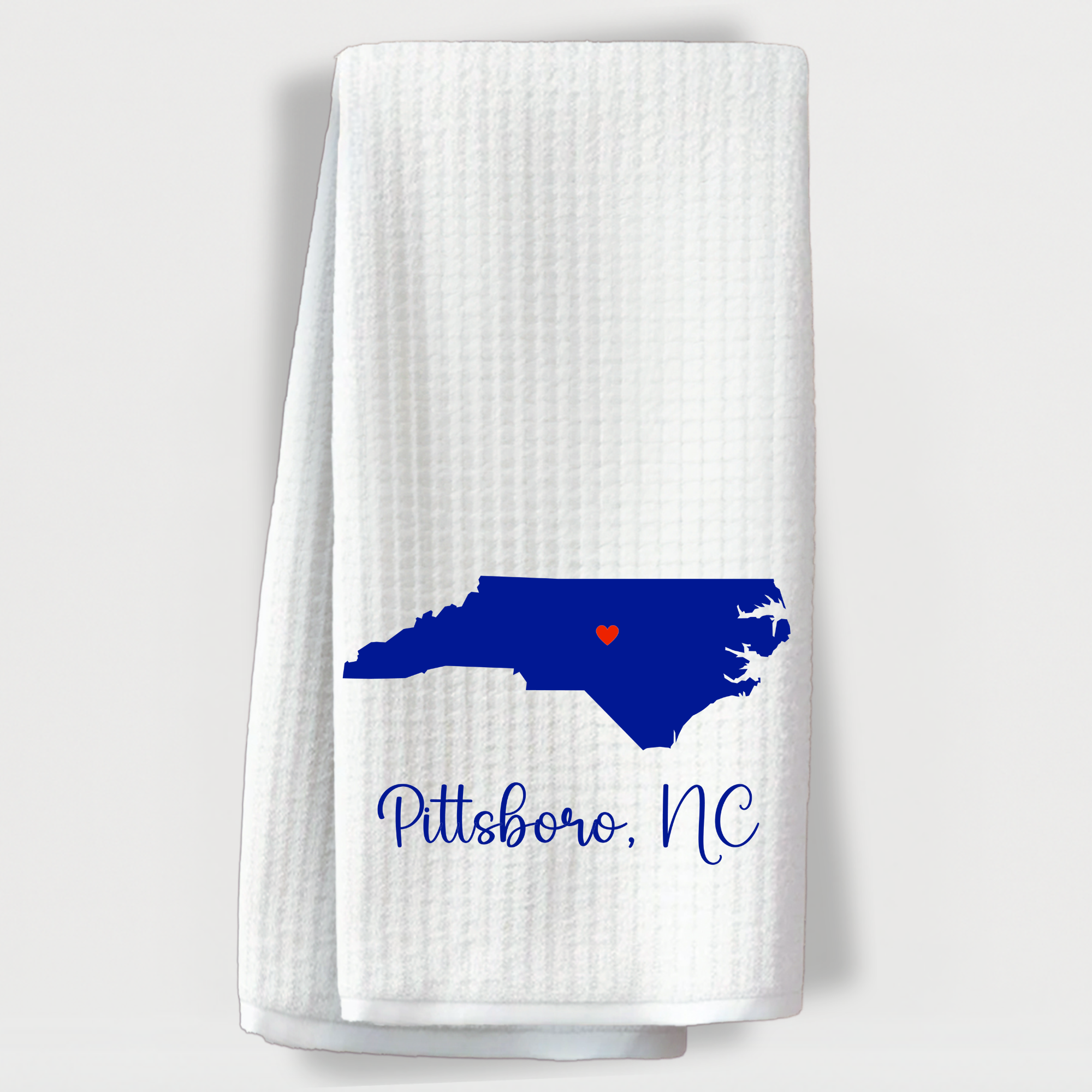 Kitchen towel with a dark blue North Carolina map and red heart highlighting Pittsboro, NC.
