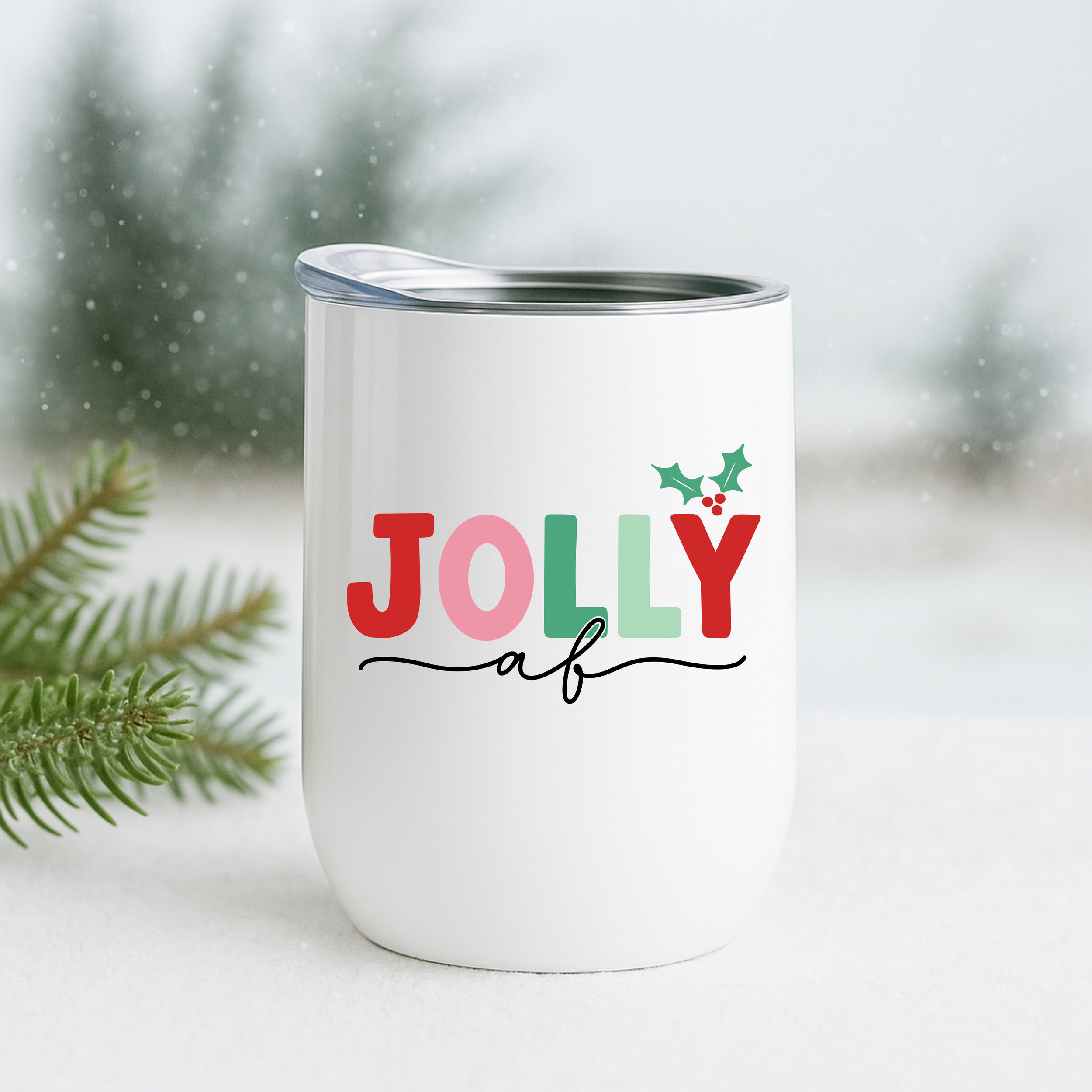 Jolly AF insulated holiday tumbler in a snowy outdoor scene with pine branches.