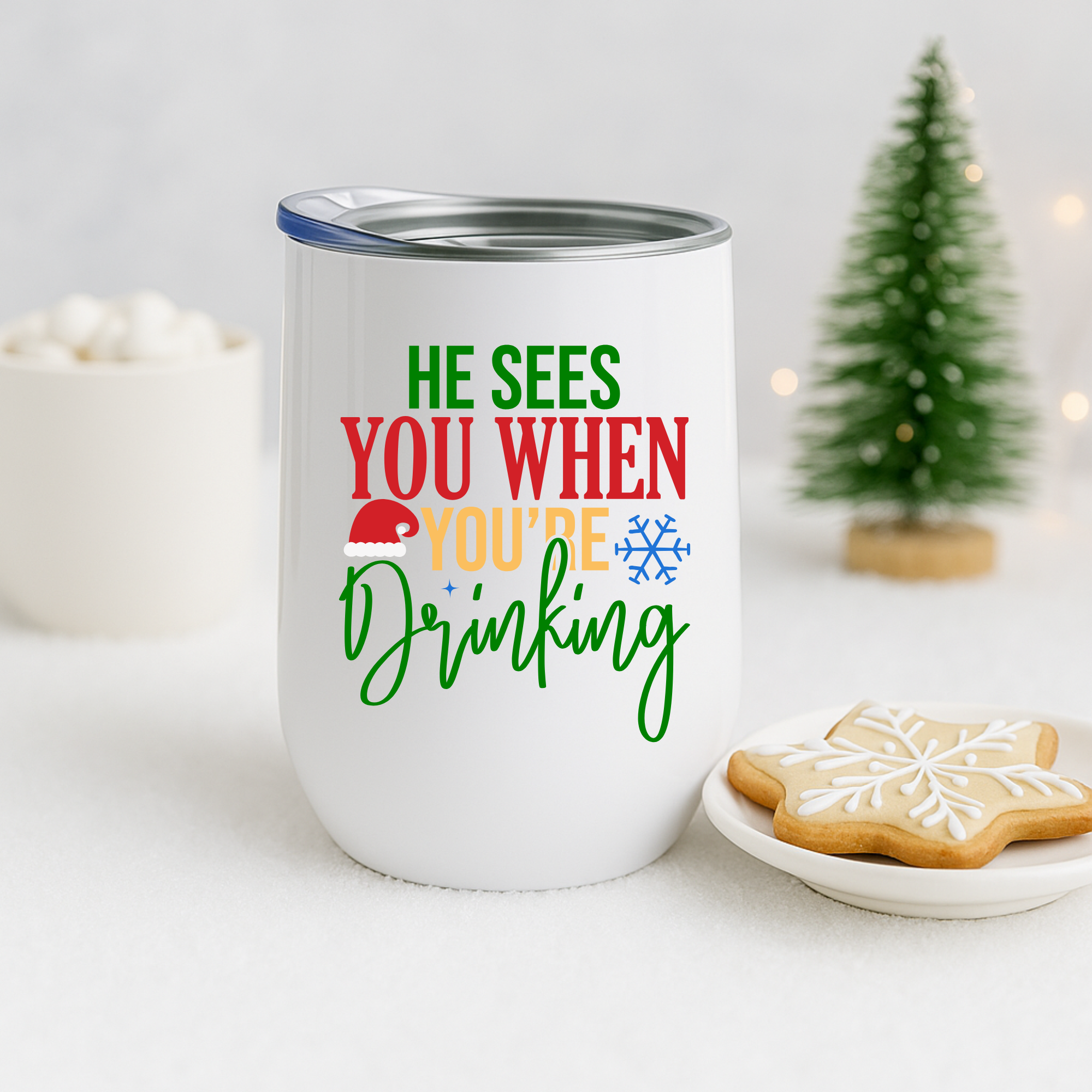 Holiday tumbler shown with snowflake cookie and winter décor featuring the “He Sees You When You’re Drinking” quote.