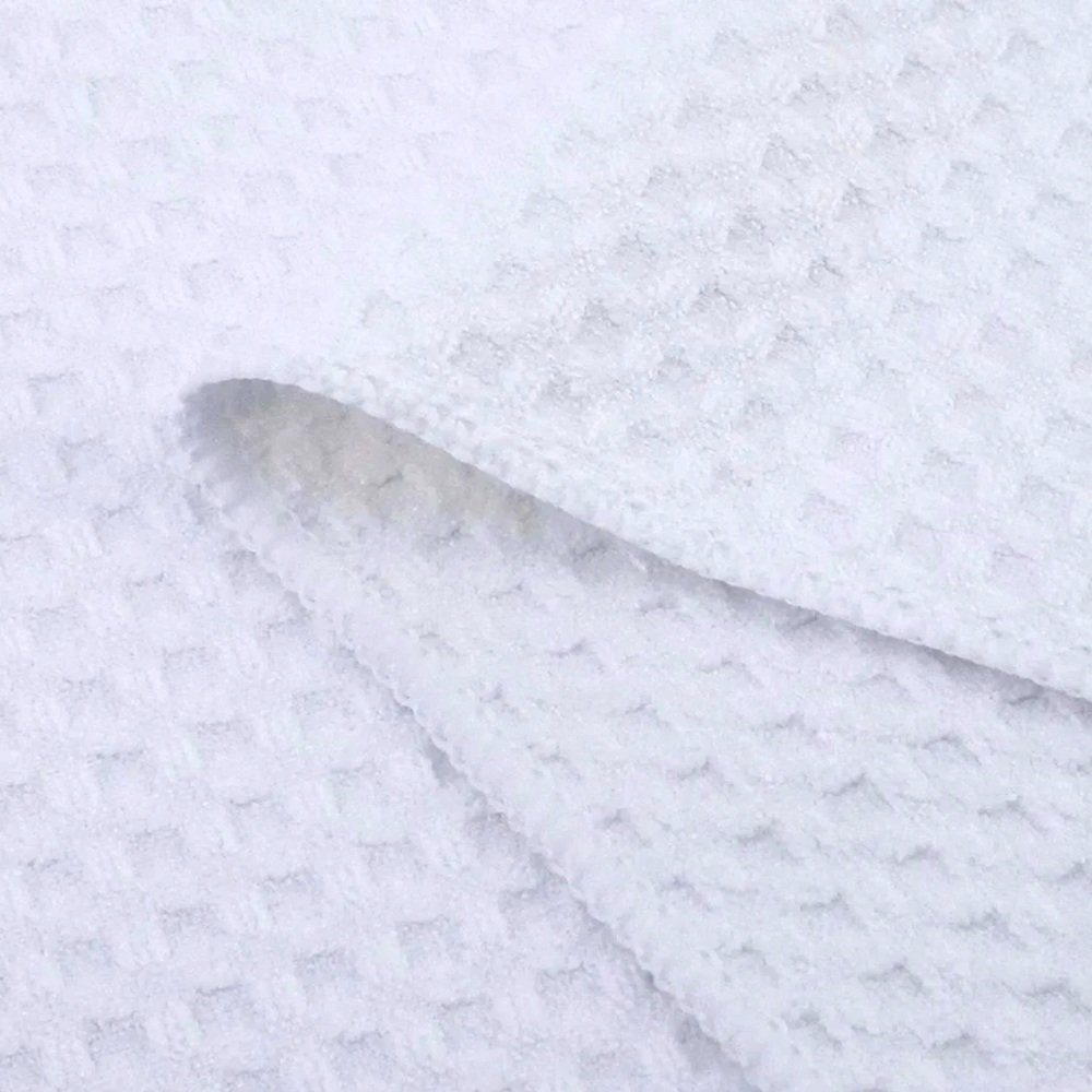 Close-up of a white waffle weave microfiber kitchen towel, highlighting its soft, absorbent texture and grid-like pattern, perfect for everyday kitchen use