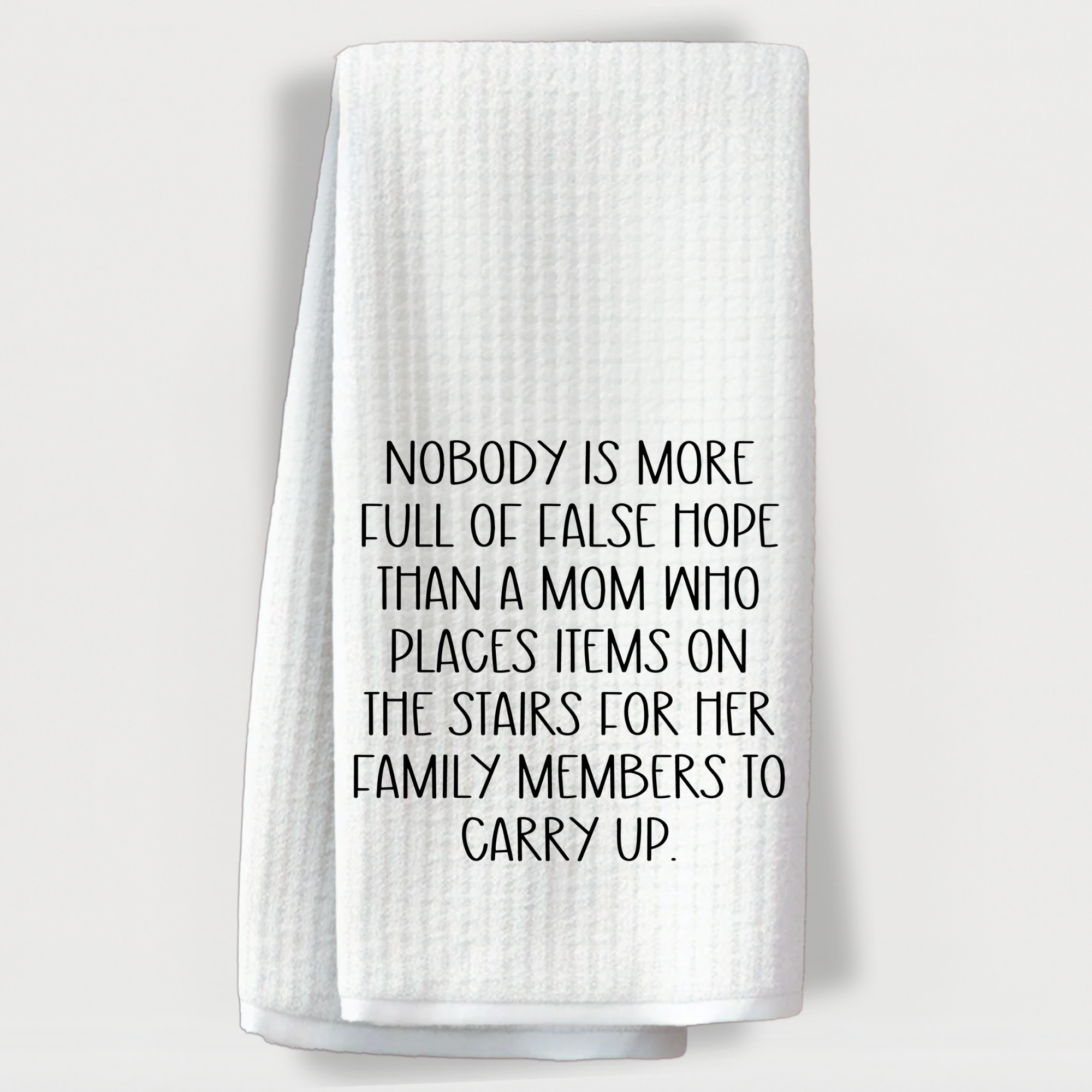 "Funny kitchen towel with the quote about moms placing items on the stairs for family to carry."