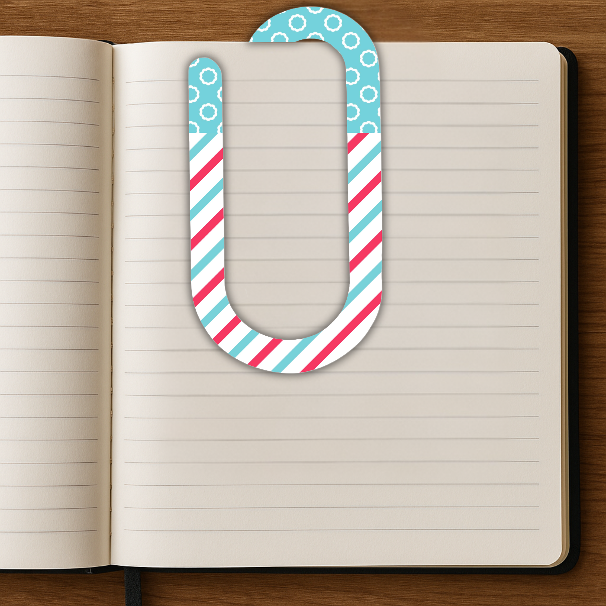 Large planner bookmark paper clip placed on an open lined notebook.