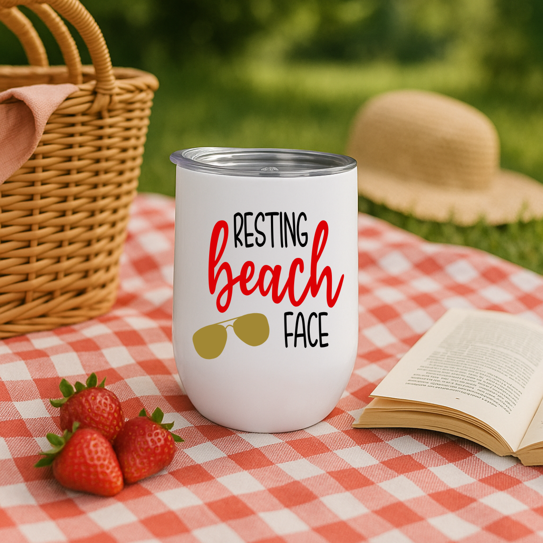 White wine tumbler on picnic blanket with “Resting Beach Face” design in red and sunglasses graphic.