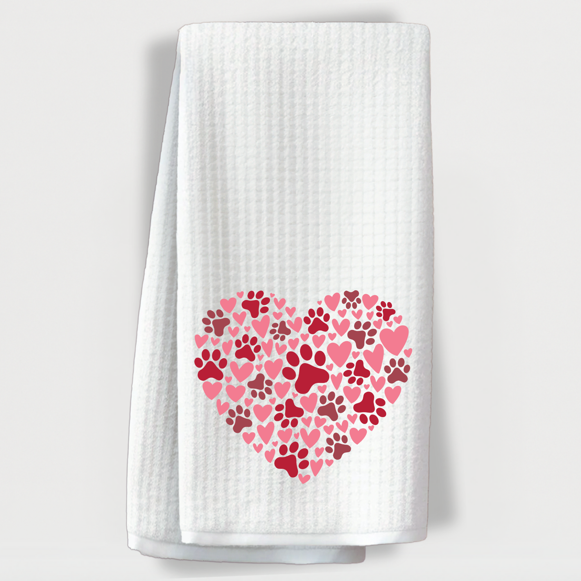 "White towel featuring a heart filled with pink and red hearts and dog paw prints."