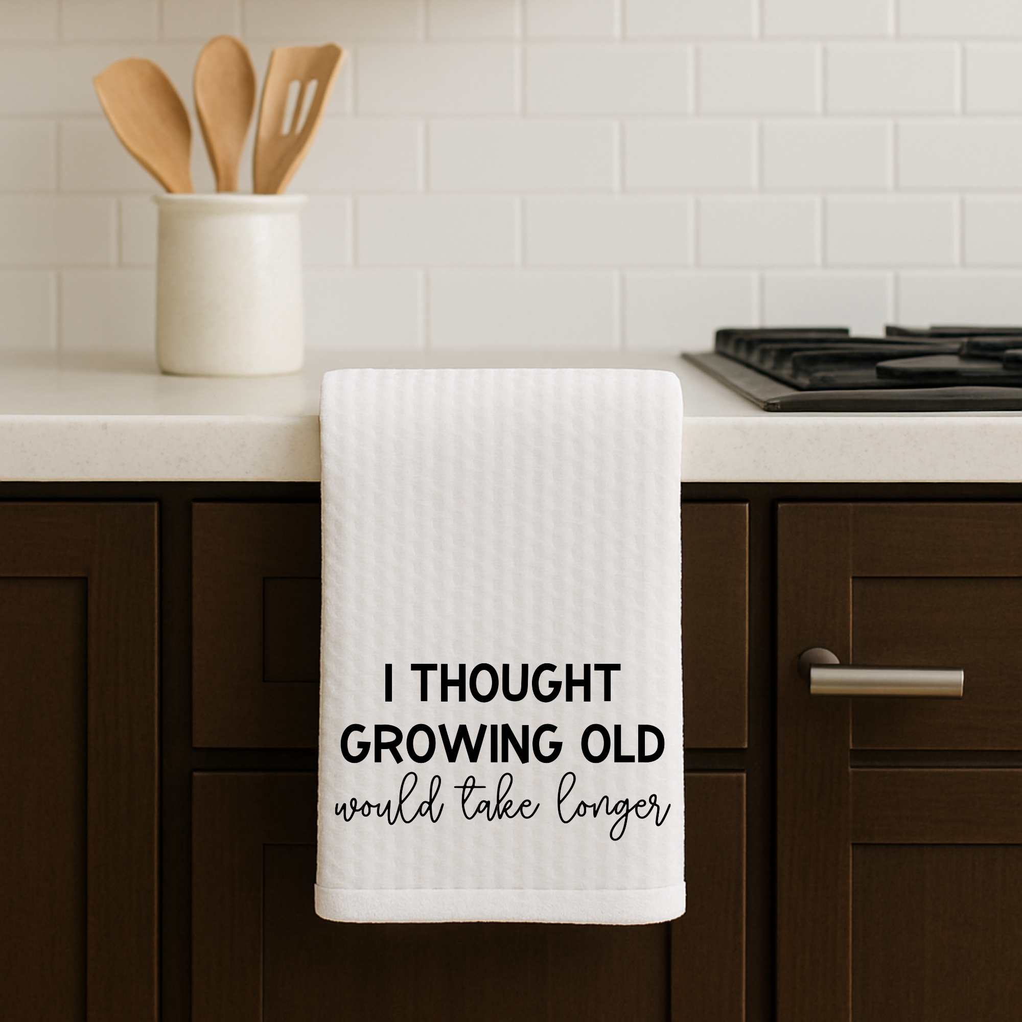 Absorbent sublimated kitchen hand towel with growing old design hanging by stove.