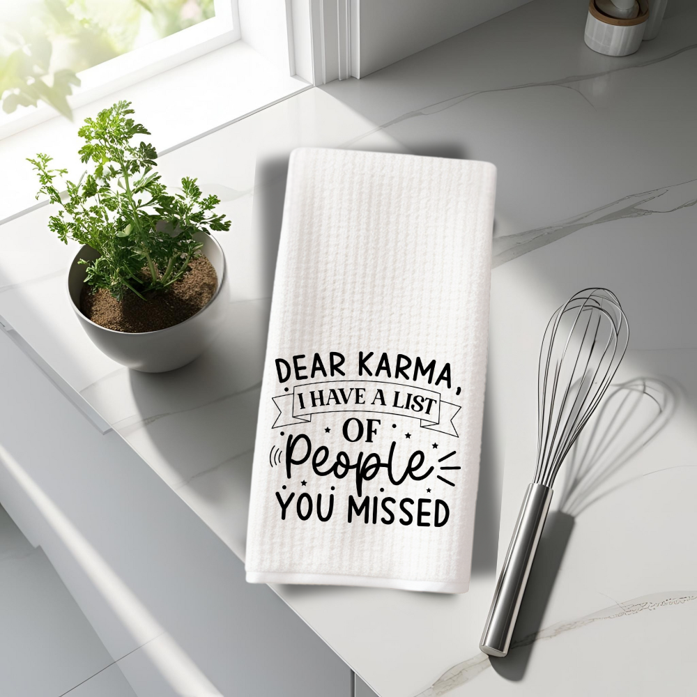 White waffle weave dish towel with a humorous "Dear Karma" message, styled in a modern kitchen setting with fresh herbs and baking tools.