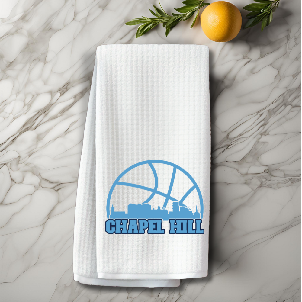 Chapel Hill basketball towel on marble surface with orange and greenery decor.