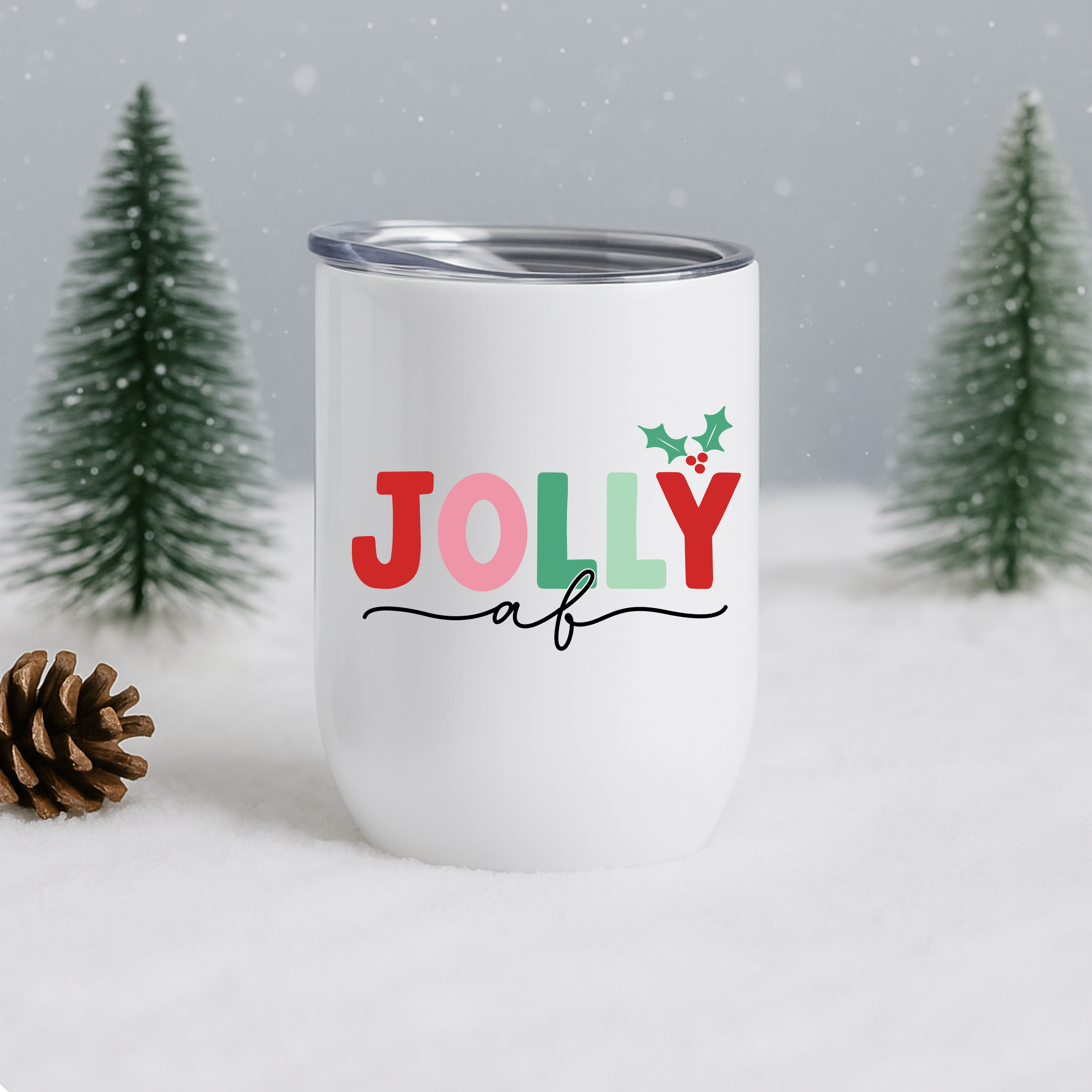 Jolly AF holiday tumbler displayed in snow with pine trees in the background.