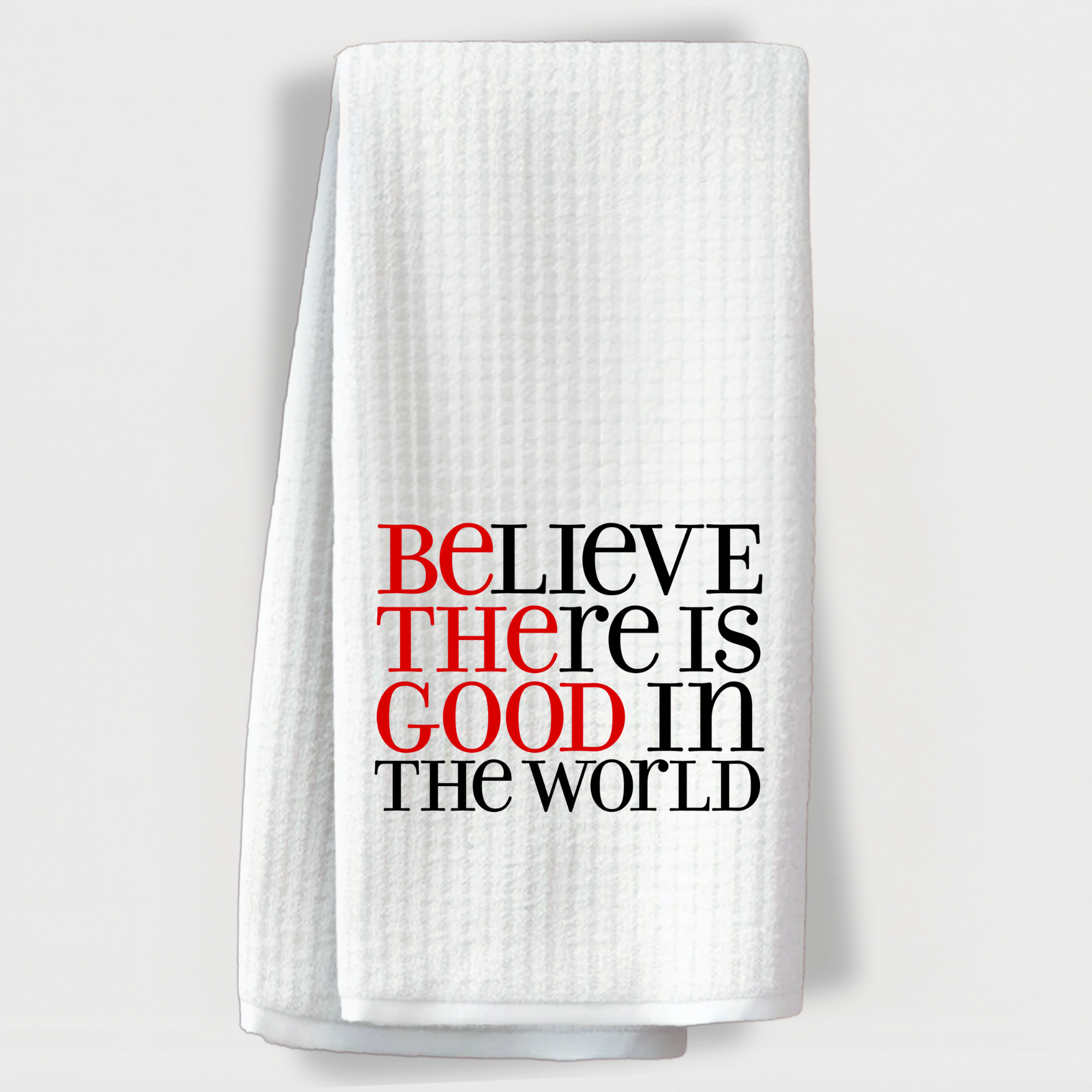 "Uplifting towel with bold typography highlighting 'Be the good' inside the phrase 'Believe there is good in the world'."
