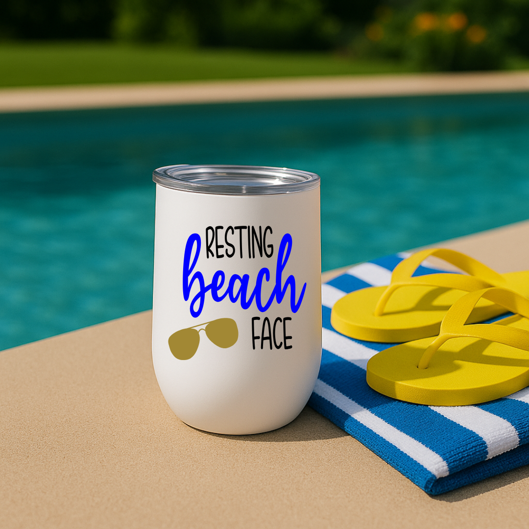 White wine tumbler by a poolside with “Resting Beach Face” design in blue and sunglasses graphic.