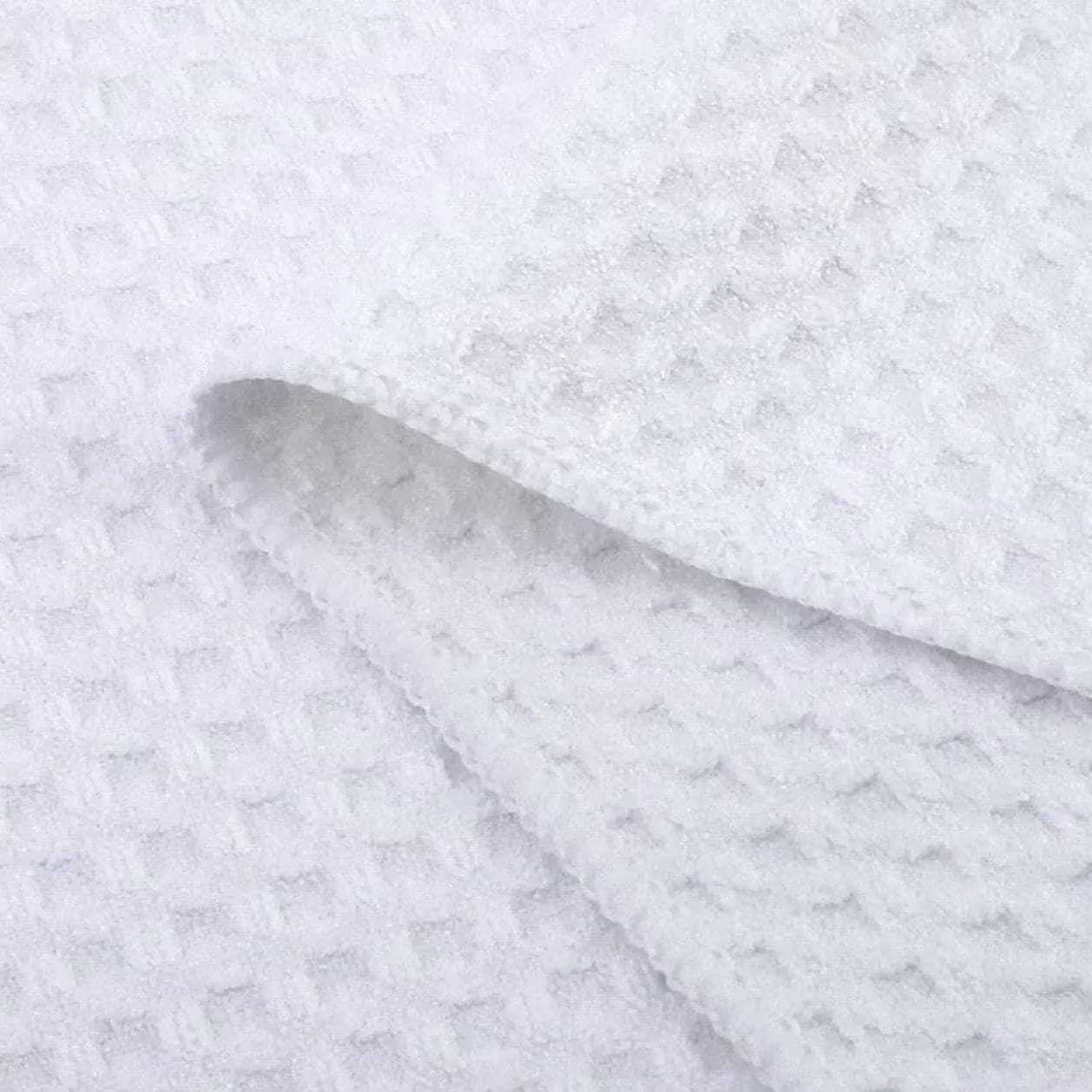 Close-up of a white waffle weave microfiber kitchen towel, highlighting its soft, absorbent texture and grid-like pattern, perfect for everyday kitchen use