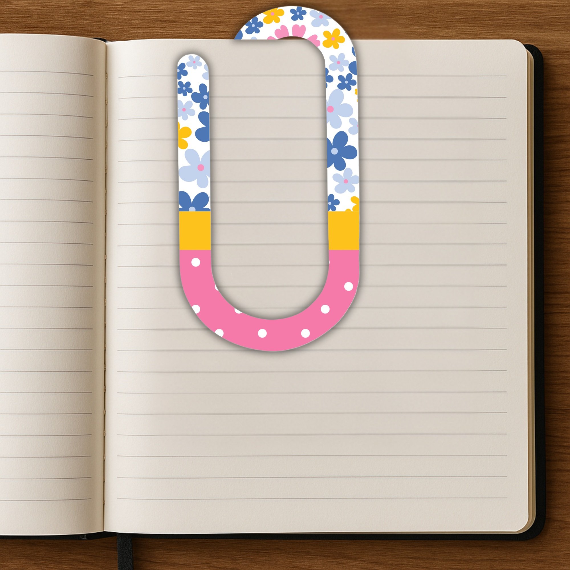 Oversized floral paper clip clipped inside open lined journal.