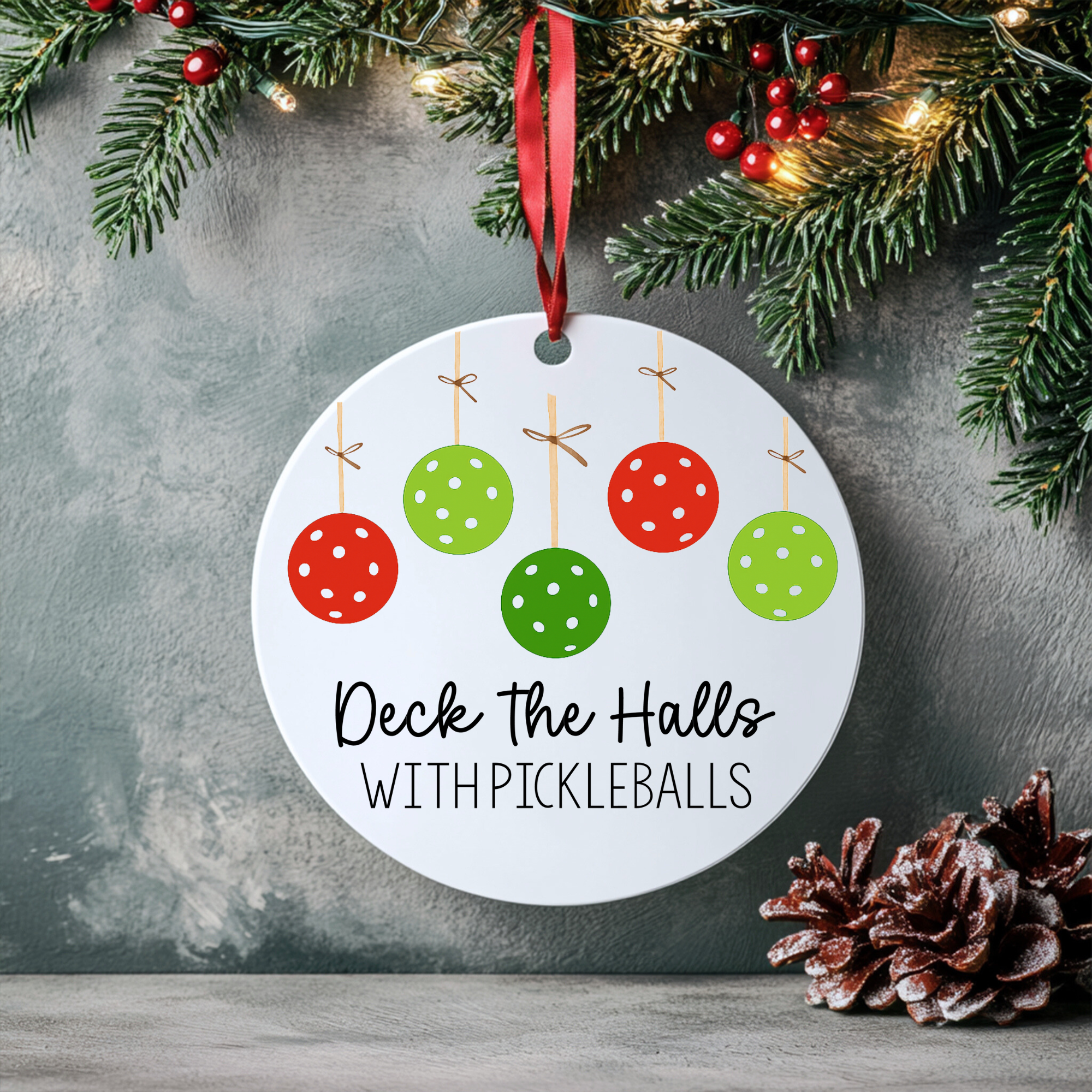 “Round Deck the Halls with Pickleballs ornament hanging on a Christmas tree with warm holiday lights.”