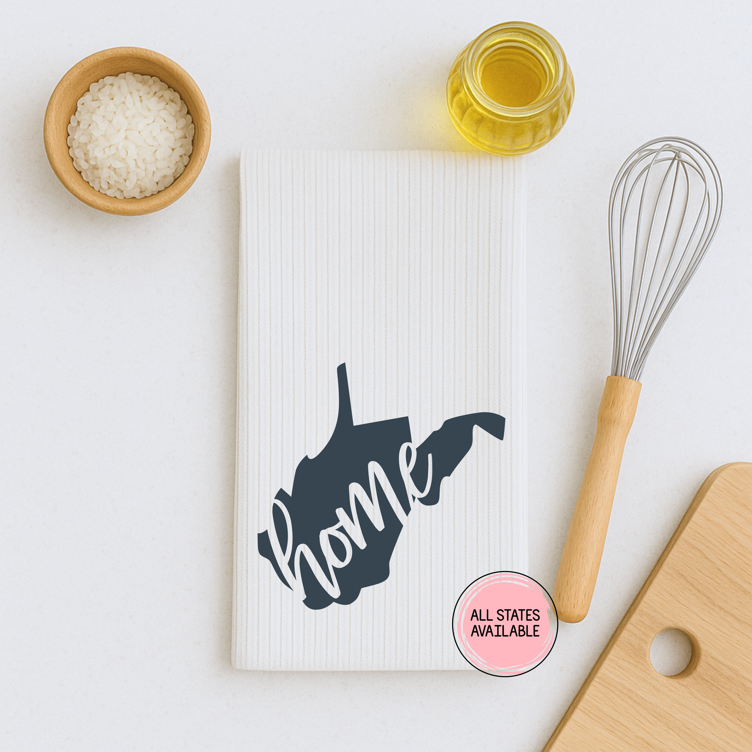 Minimal flat lay of a white waffle weave kitchen towel featuring a dark gray West Virginia home state design.