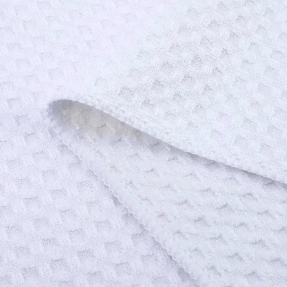 Close-up of a white waffle weave microfiber kitchen towel, highlighting its soft, absorbent texture and grid-like pattern, perfect for everyday kitchen use
