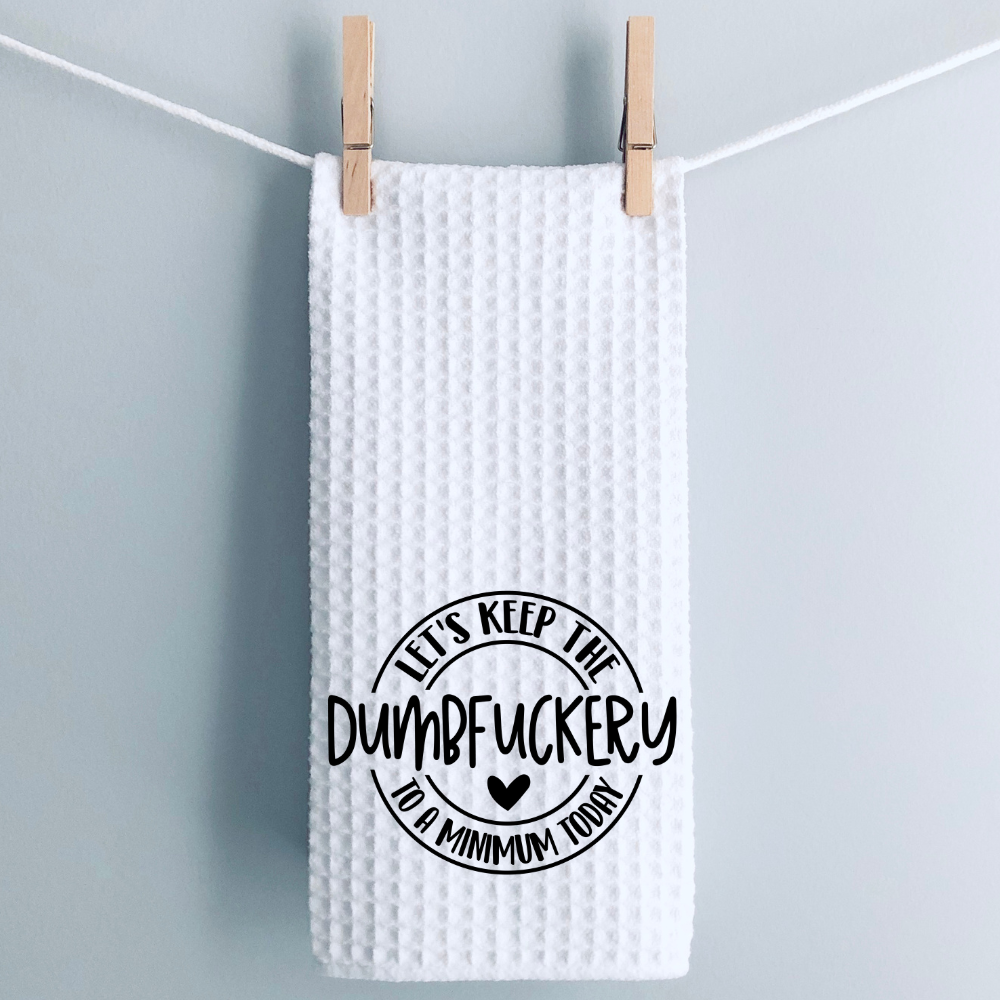 Minimalist laundry-style display of a white waffle kitchen towel with a bold and funny printed quote.