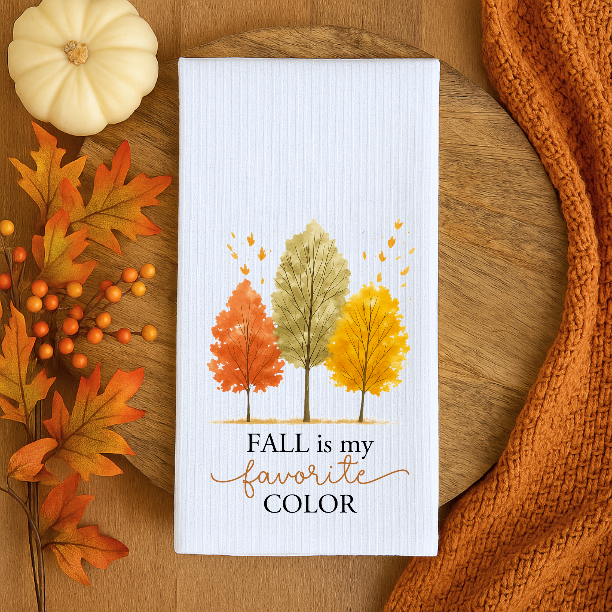 Thanksgiving kitchen towel with orange, green, and yellow tree design displayed with pumpkin and autumn decor.