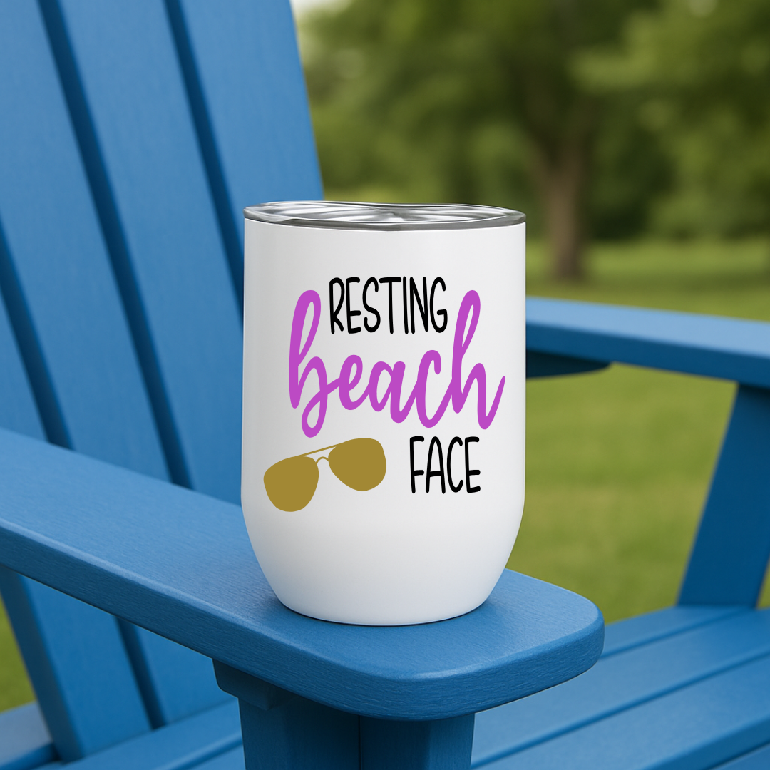 White wine tumbler on blue chair with “Resting Beach Face” design in amethyst purple and sunglasses graphic.
