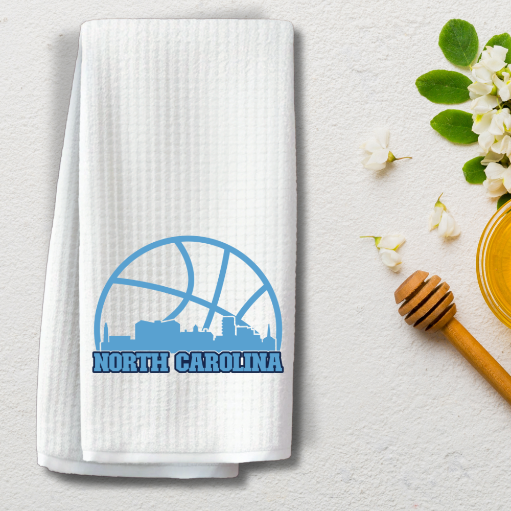 North Carolina basketball skyline towel styled with flowers and honey dipper on textured white background.