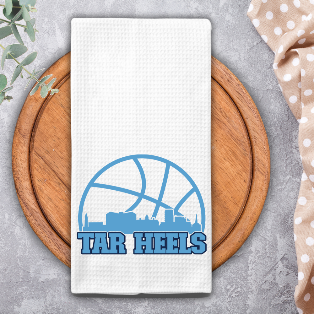 Tar Heels waffle towel on circular wooden board with neutral gray background and polka dot napkin.
