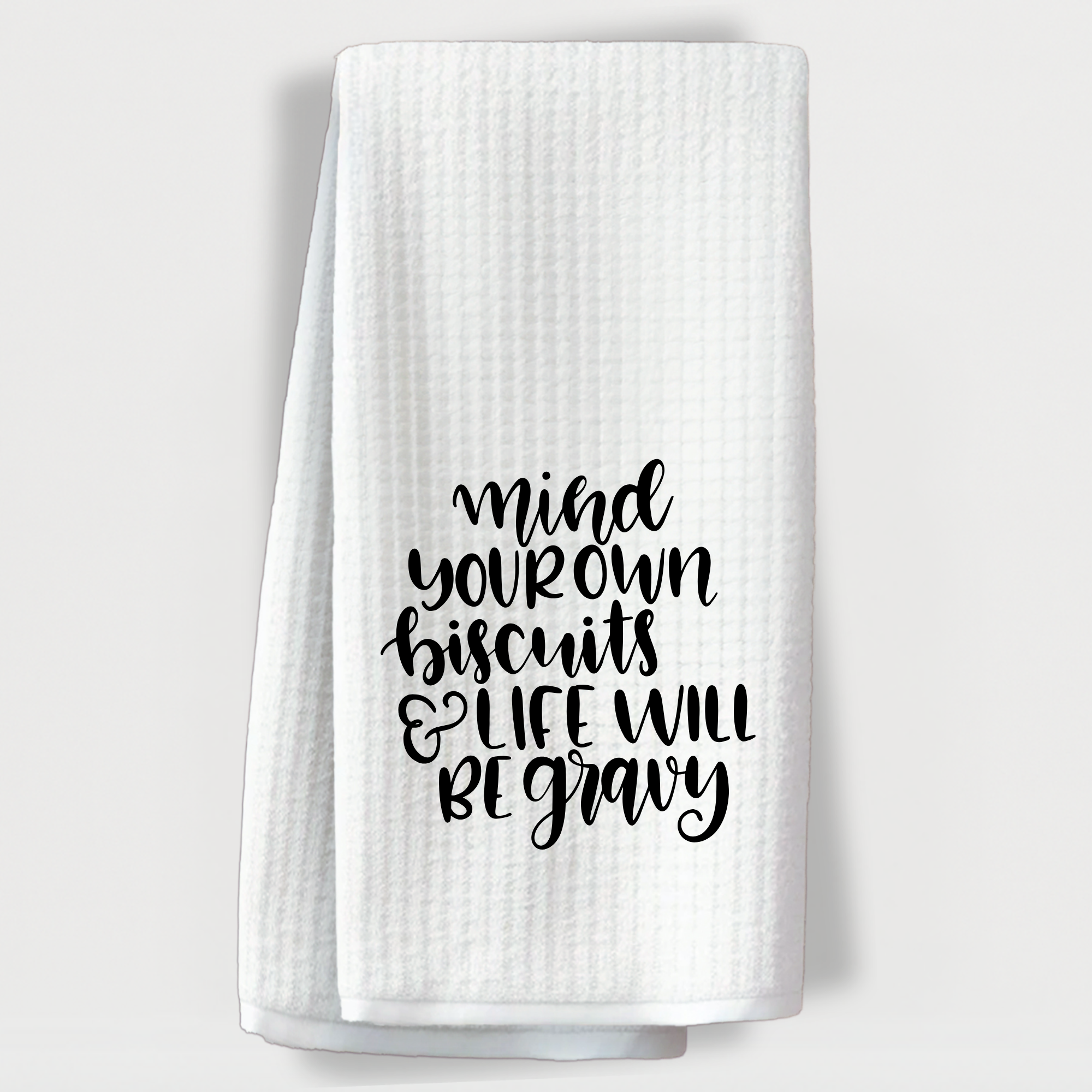 "Funny kitchen towel with the phrase 'Mind your own biscuits and life will be gravy' in bold script."