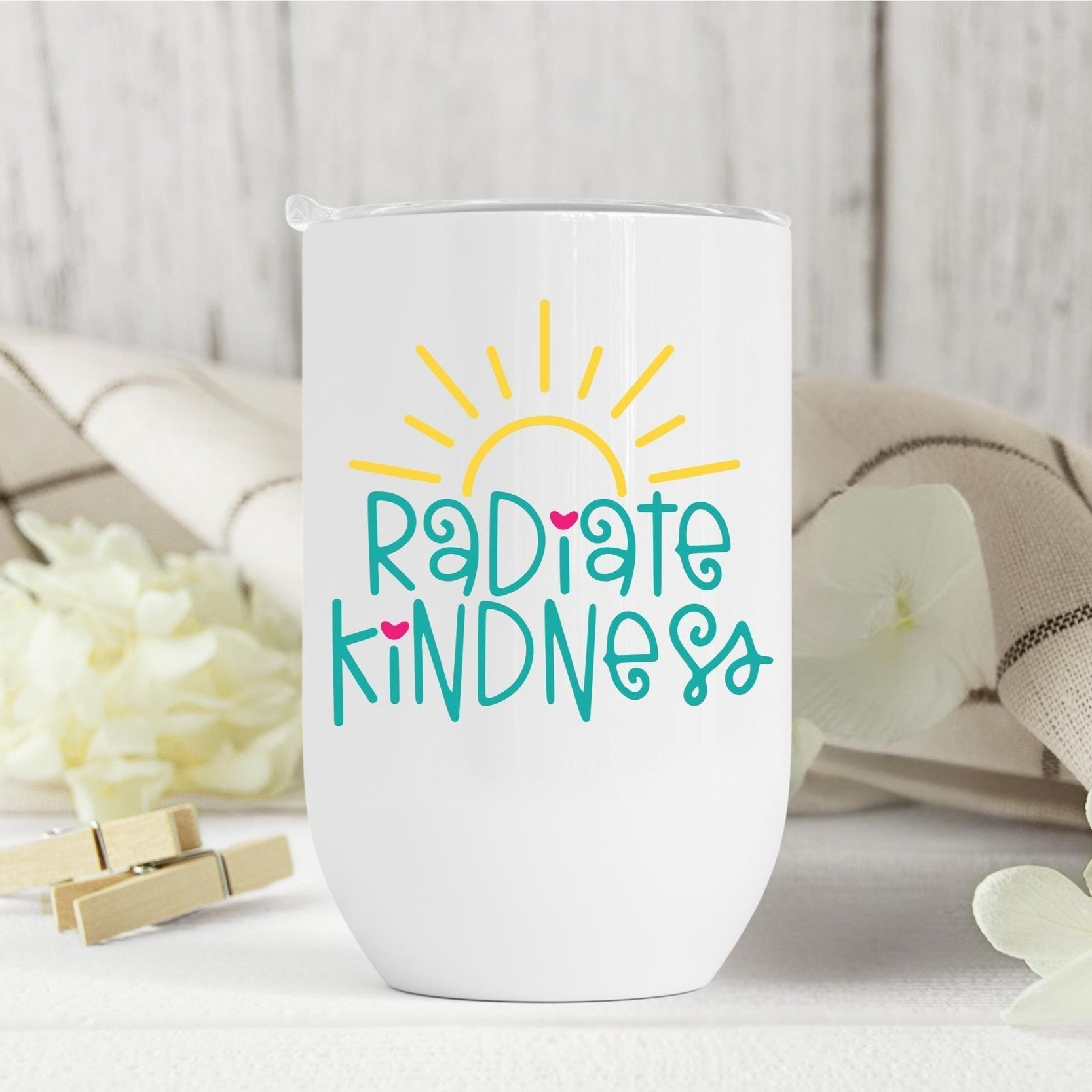 Inspirational wine tumbler with "Radiate Kindness" quote, styled with flowers and cloth – Perfect self-care gift for moms, friends, and coworkers.