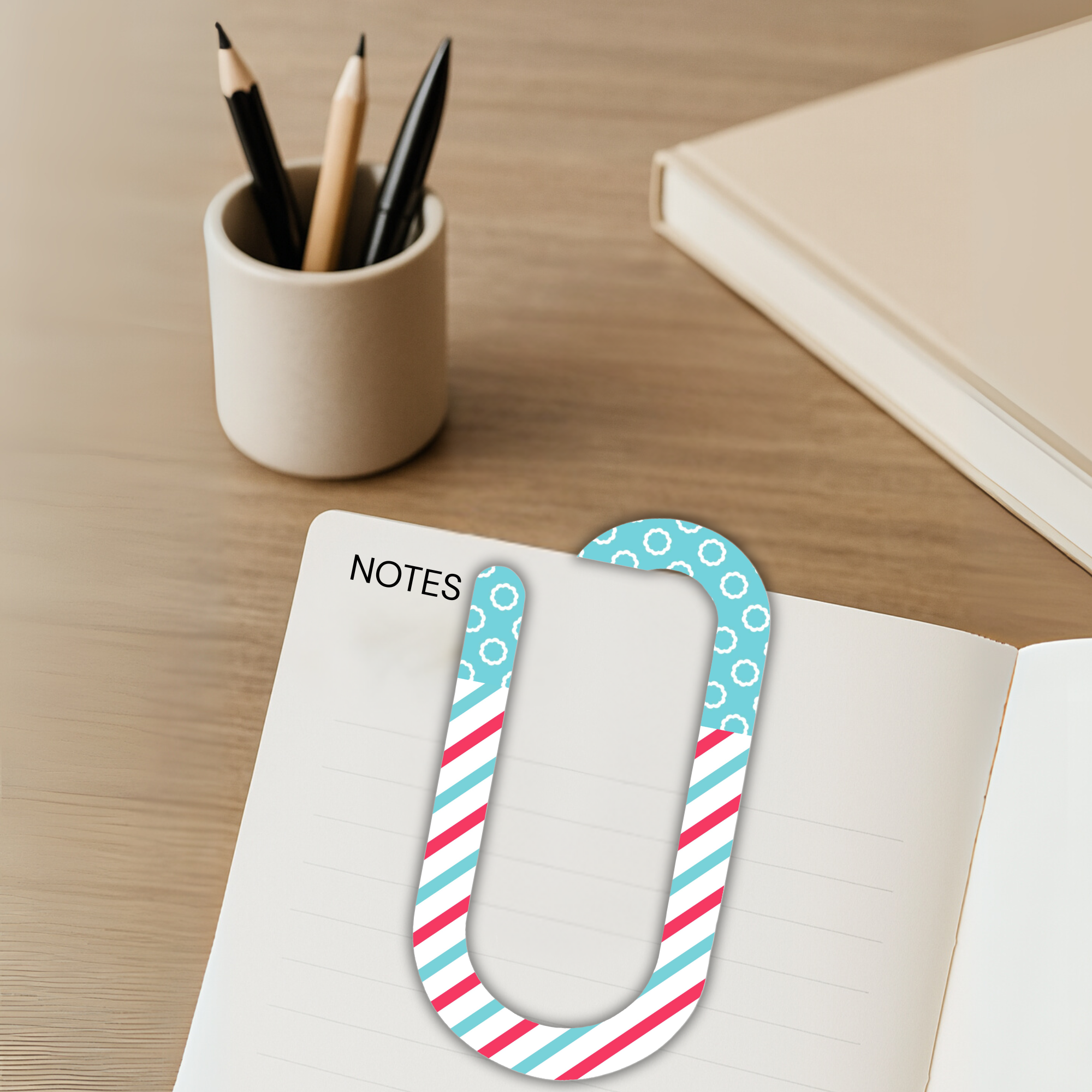 Jumbo paper clip used as a notes bookmark with desk accessories in view.