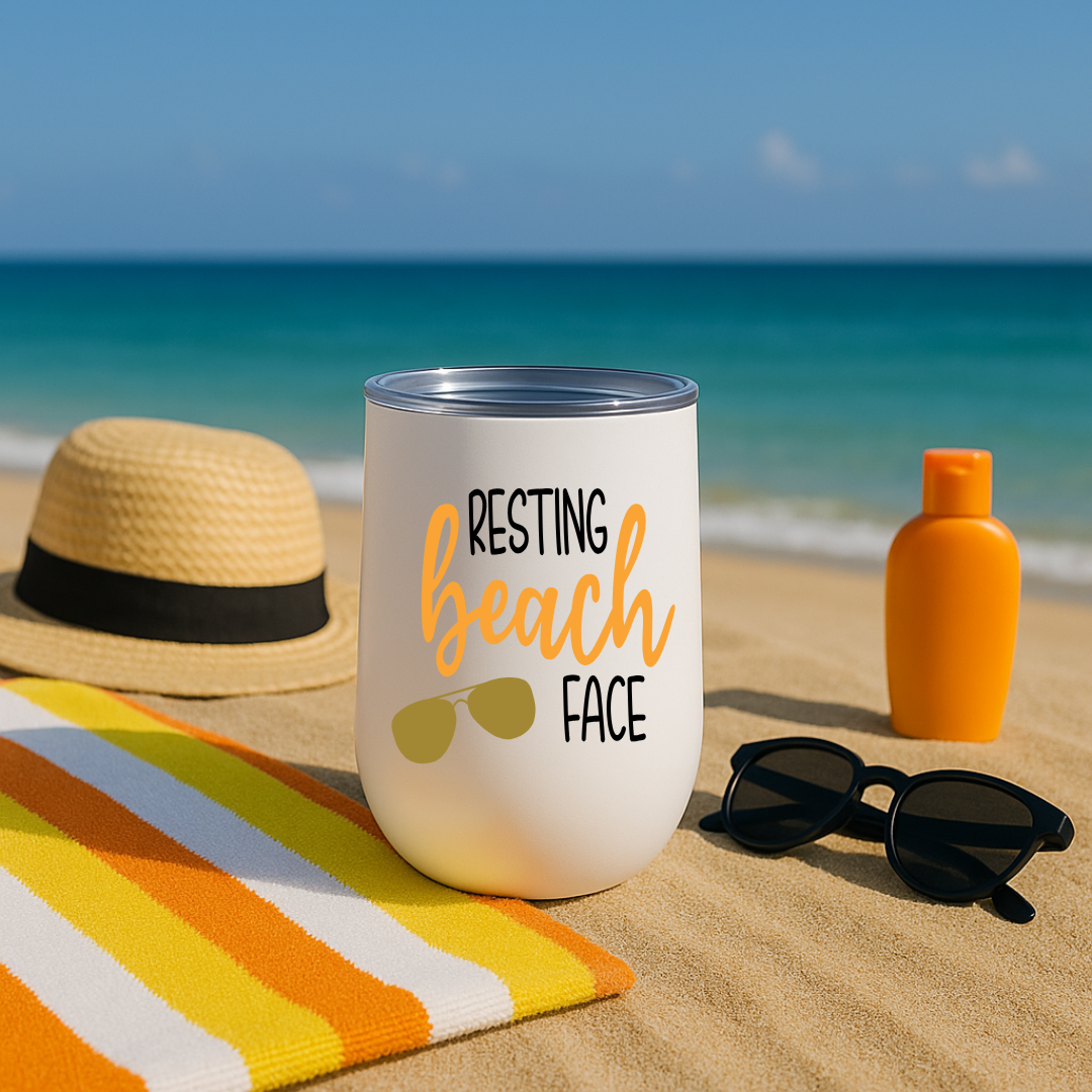 White wine tumbler on sandy beach with “Resting Beach Face” design in orange and sunglasses graphic.