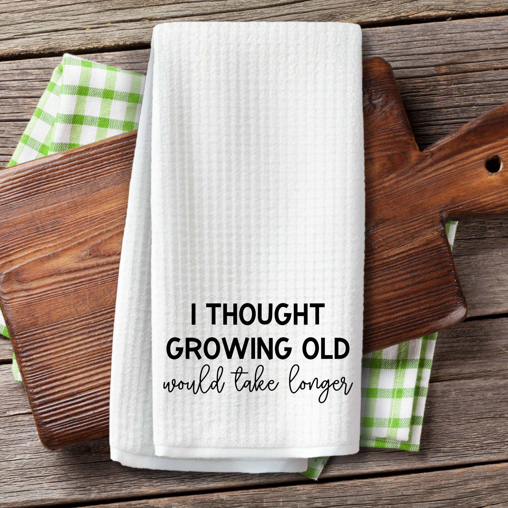 Funny waffle weave towel with aging quote displayed on wood cutting board kitchen decor.