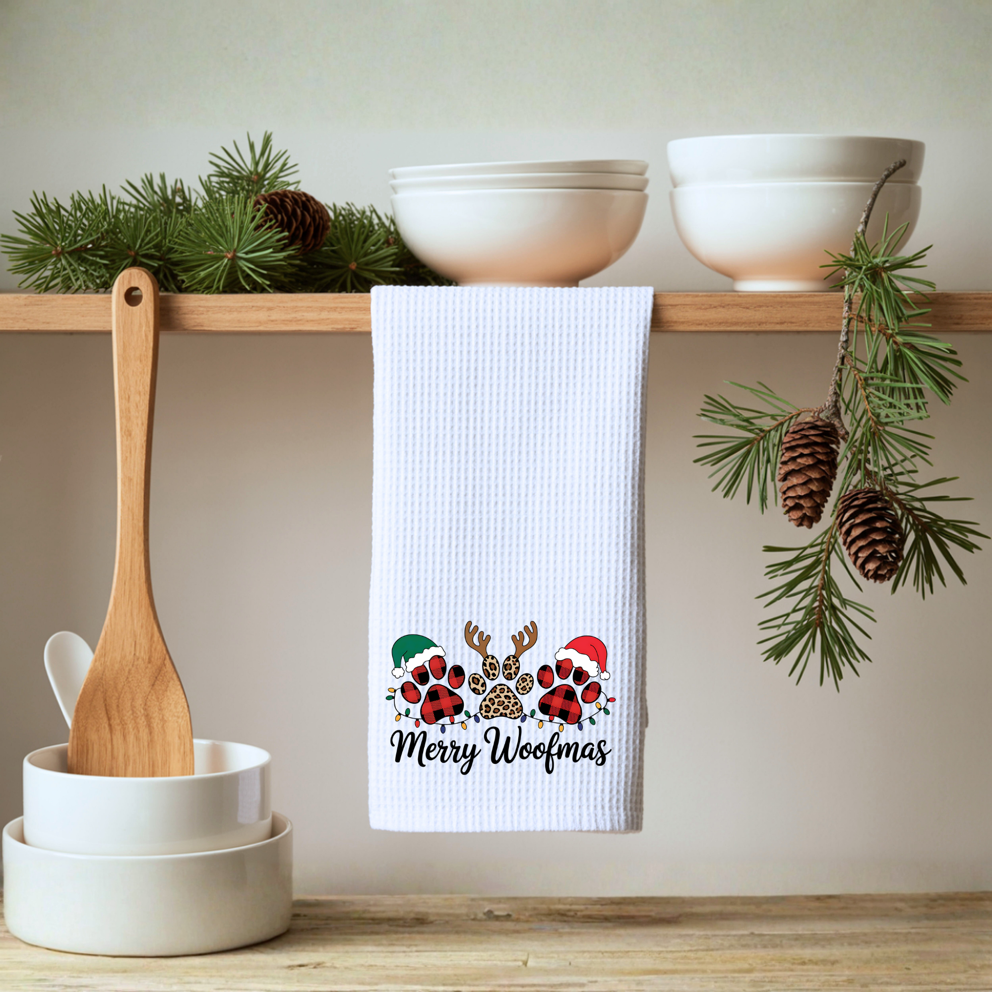 Merry Woofmas dog Christmas kitchen towel hanging from a kitchen shelf with neutral holiday decor.