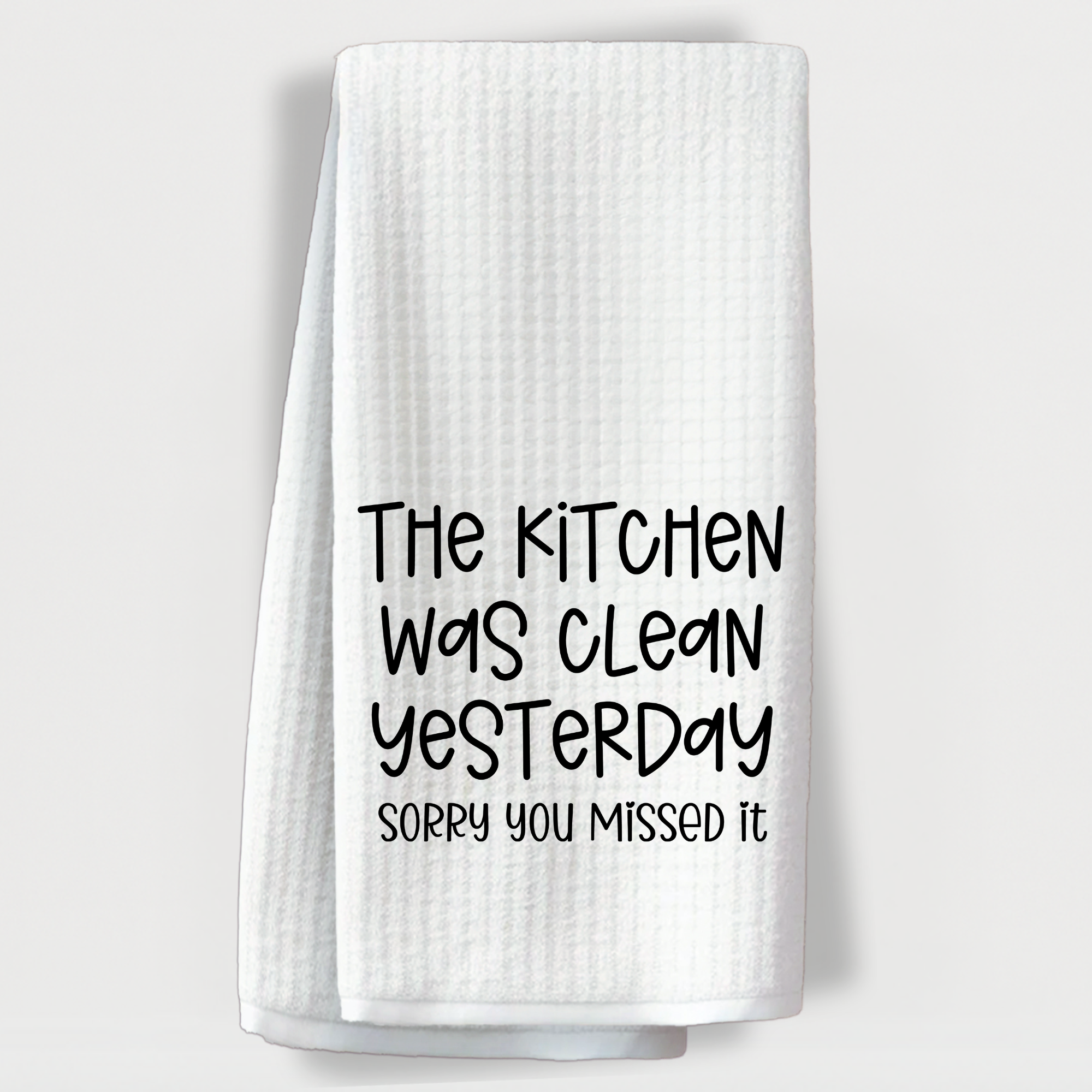 "Sarcastic towel that says 'The kitchen was clean yesterday, sorry you missed it' in playful black font."